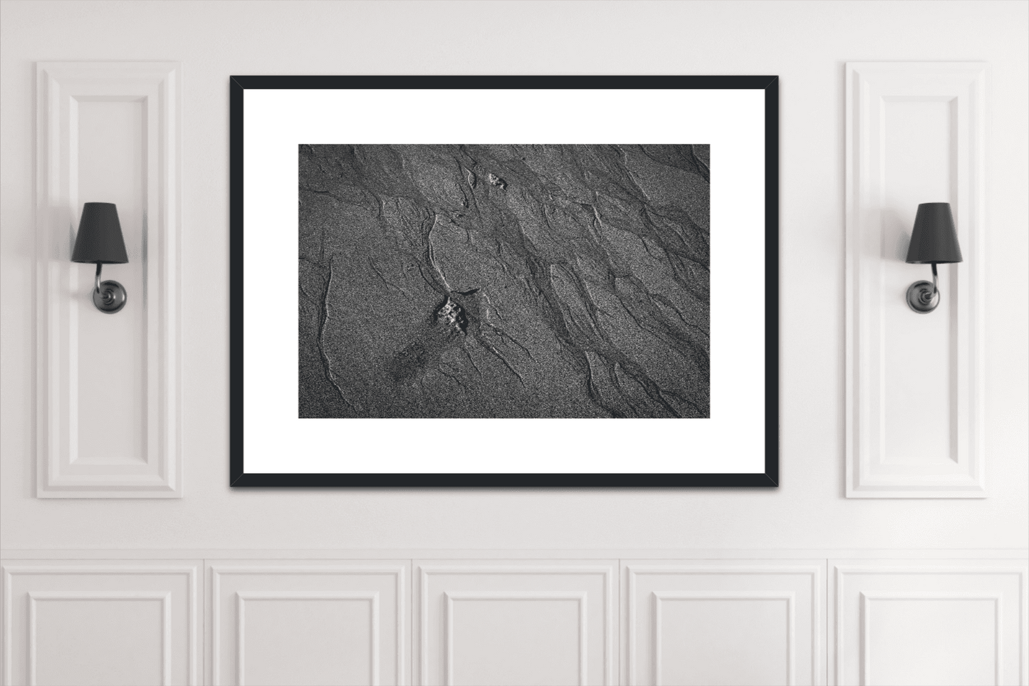 Traces #2 framed black and white sand pattern print mounted between wall sconces. Sophisticated artwork for classic white-paneled interiors.