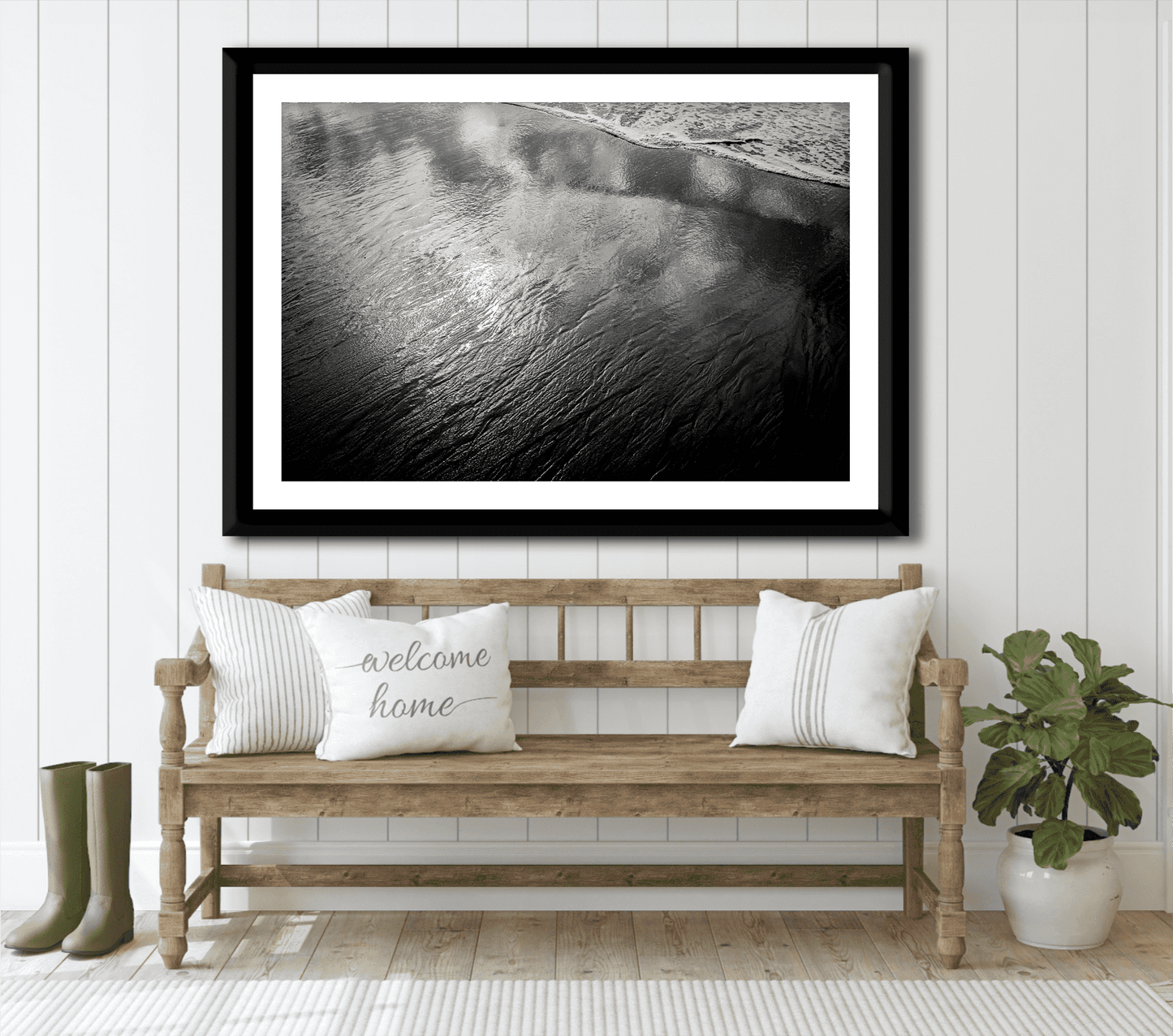 Coastal-themed entryway with framed 'Traces #4 – Reflections at the Sea Edge, Maine' black and white print above wooden bench and welcome pillow.