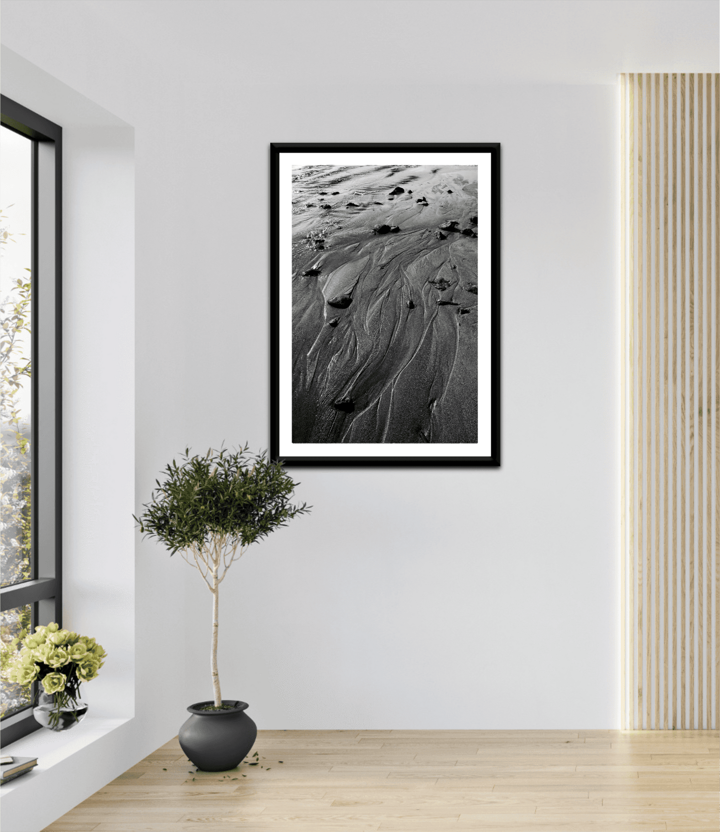 Framed 'Traces #3' black and white sand artwork displayed in a bright, modern room with natural light and minimalist decor elements.