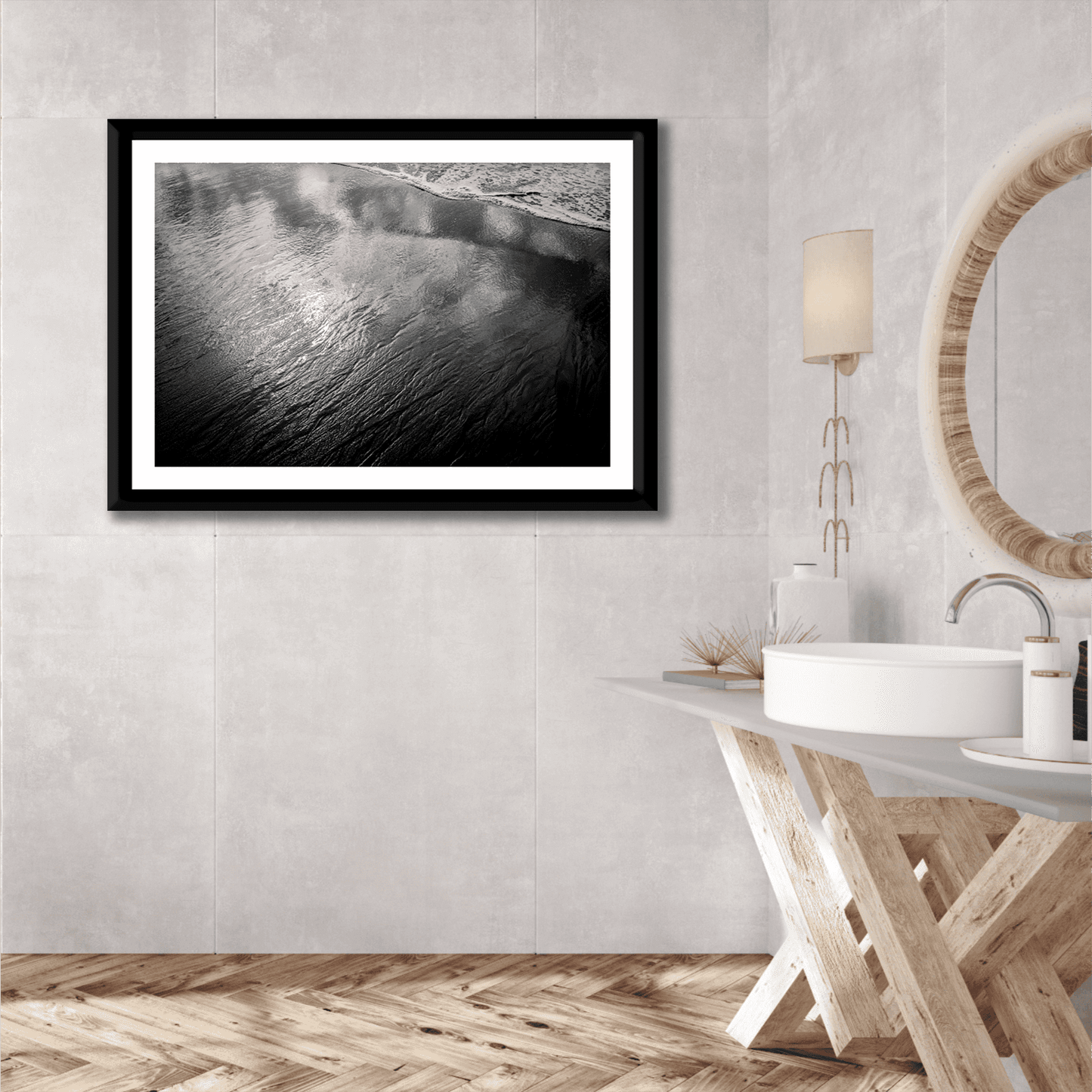 Elegant bathroom interior with framed black and white print 'Traces #4 – Reflections at the Sea Edge, Maine' above modern vanity and round mirror.
