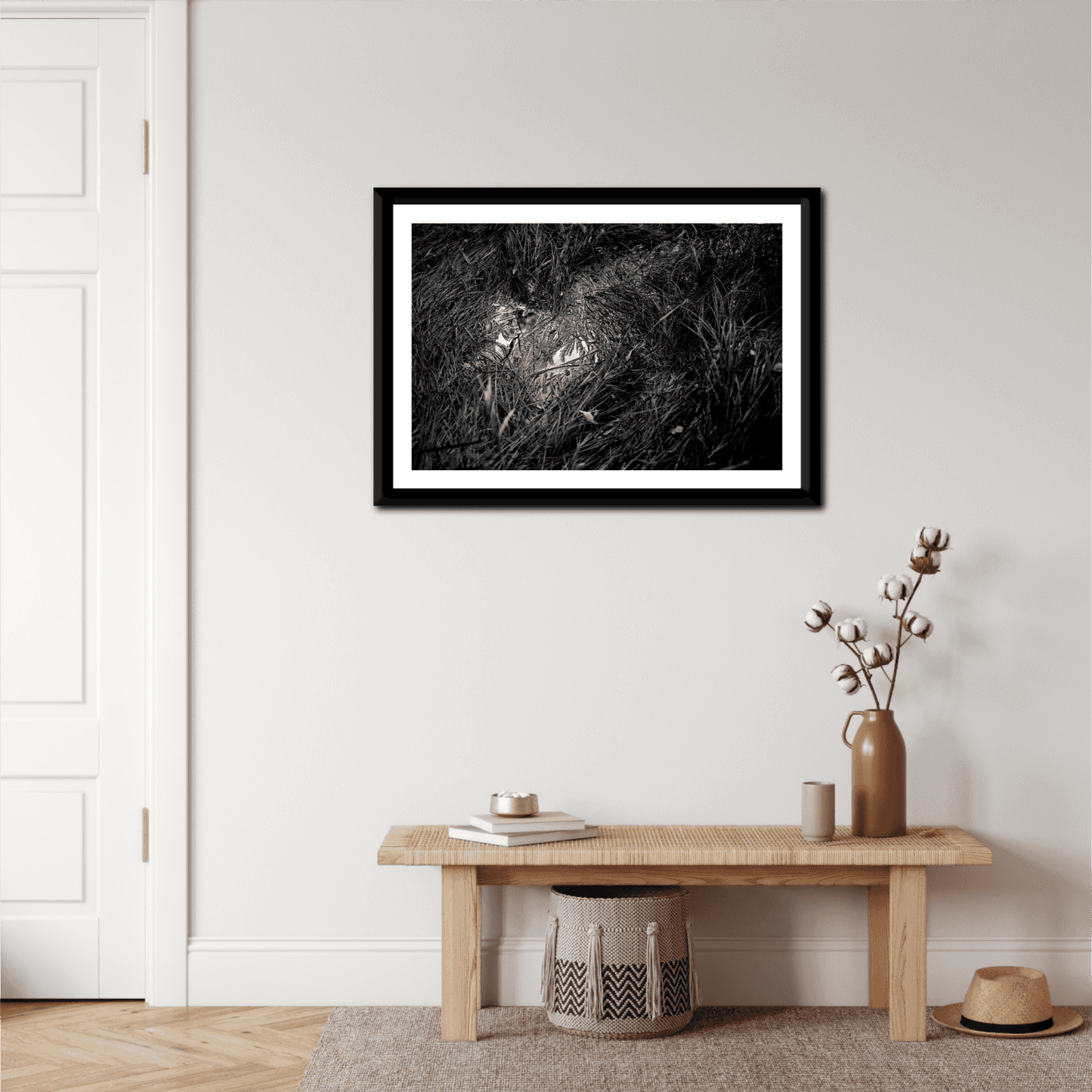 'Water & Reeds – A Scene in Acadia National Park in Black and White' framed fine art print hanging above a wooden bench in a cozy, neutral-toned entryway.