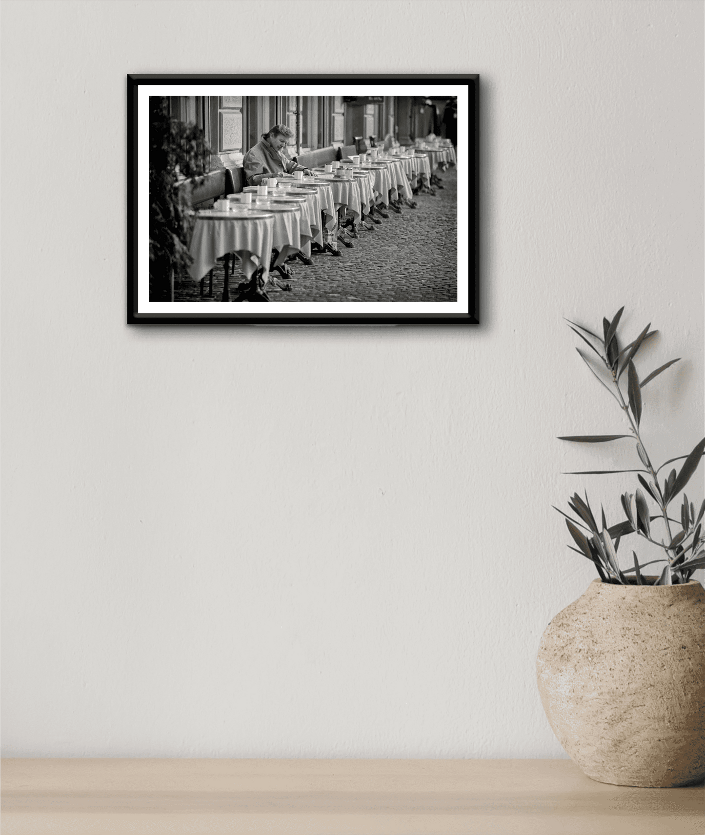 Zurich Series #3 – The Man at the Café, Zurich in Black and White – Fine Art Print by Michael Hart hung on a neutral wall with a ceramic vase. A serene monochrome artwork enhancing minimalist interior aesthetics.