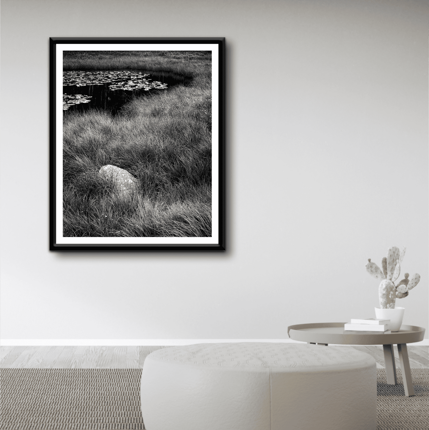Minimalist living room featuring 'Pond Boulder' serene landscape photography print in black frame, highlighting tranquil mountain pond scenery.