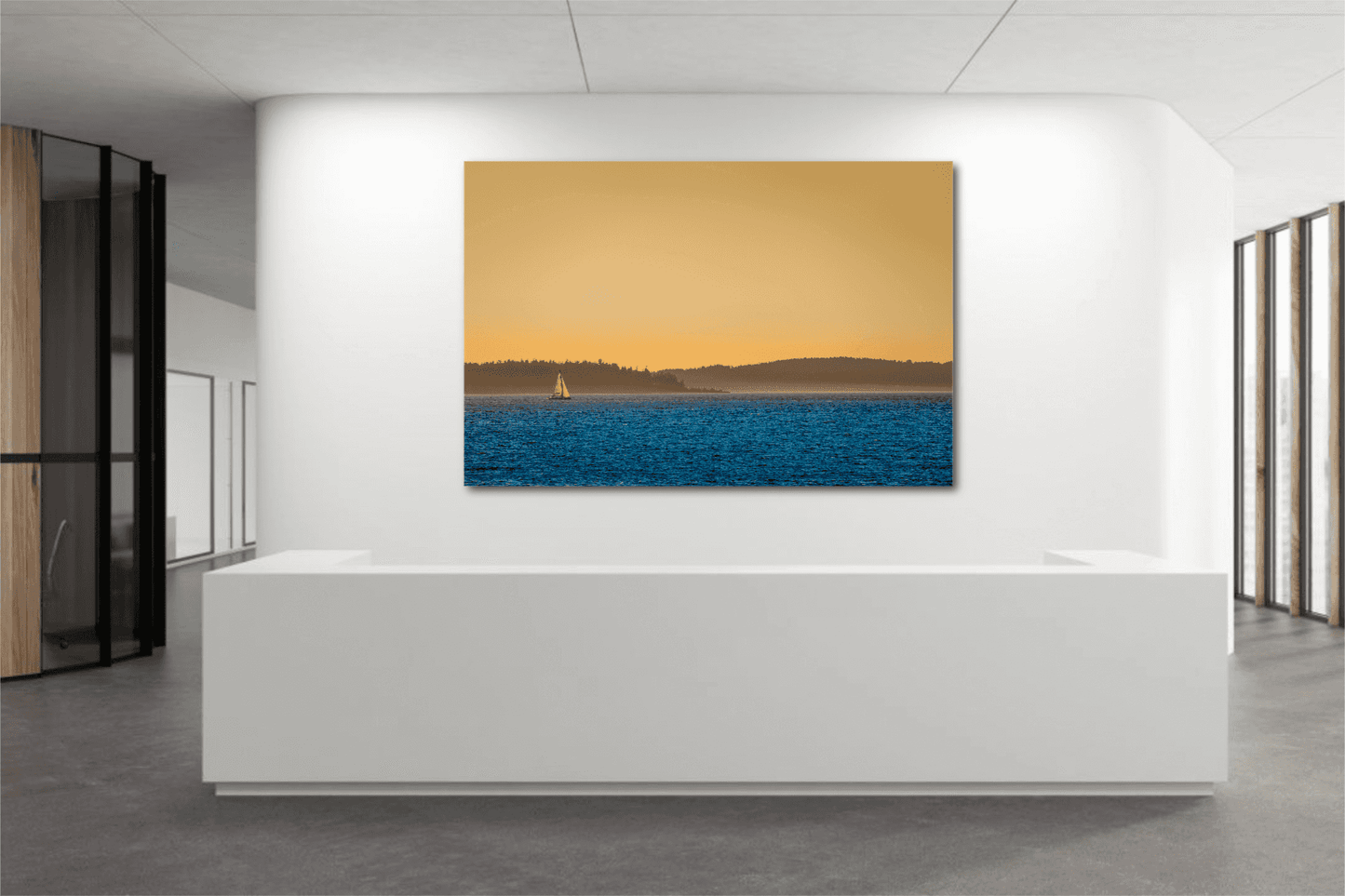 Golden Hour Sailboat fine art print displayed in a modern office lobby, showcasing Puget Sound's sunset hues and tranquil maritime scene.