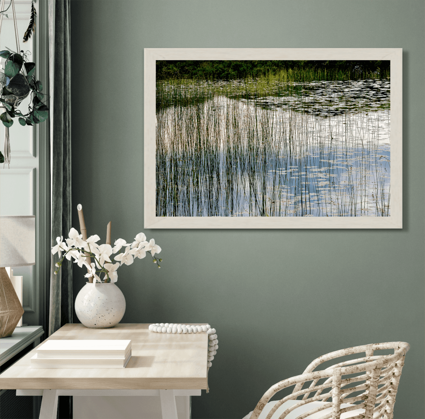 Scottish Highlands wall art featuring reeds and reflections, framed and styled in a green-toned room with elegant floral accents and wicker chair.