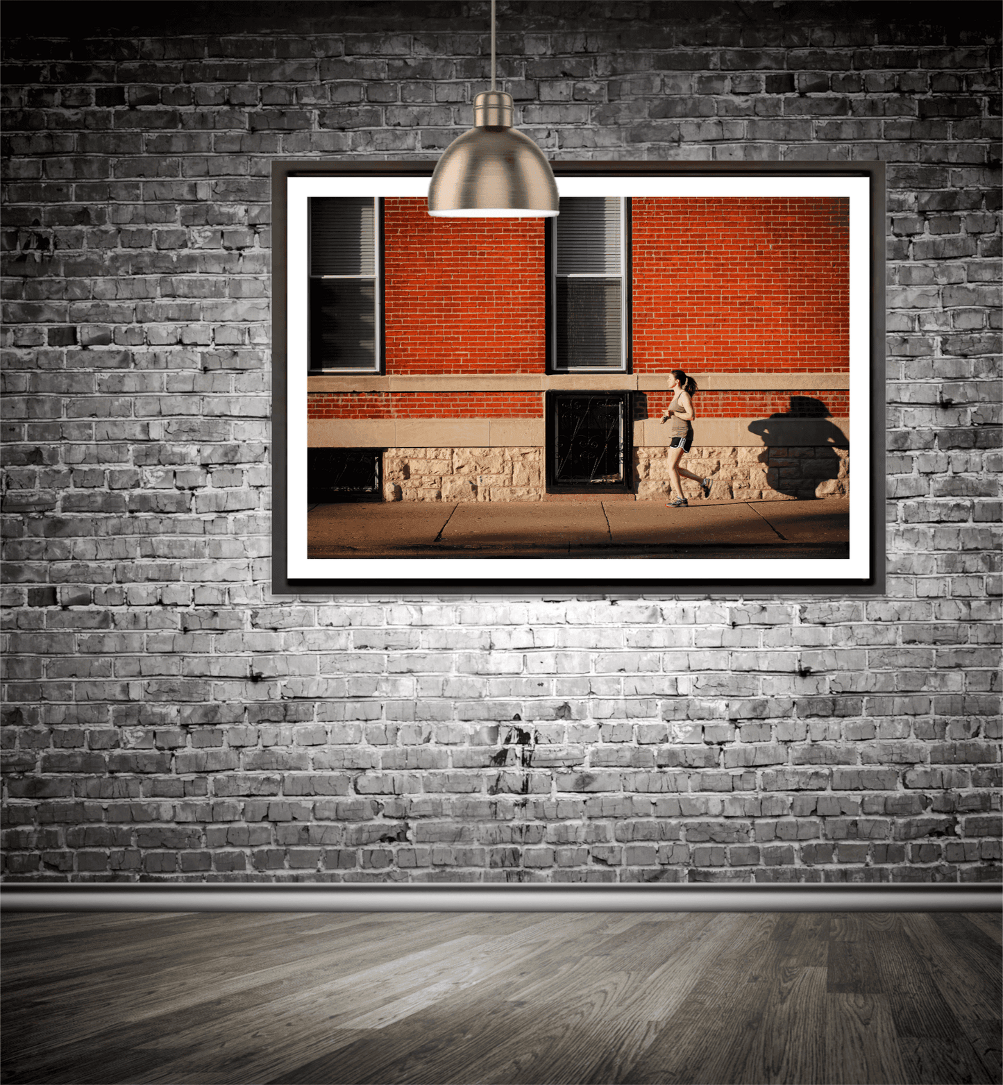 Framed print in a rooms setting of woman jogging along a sidewalk in Chicago, in the early evening summer light, against. red brick facade.