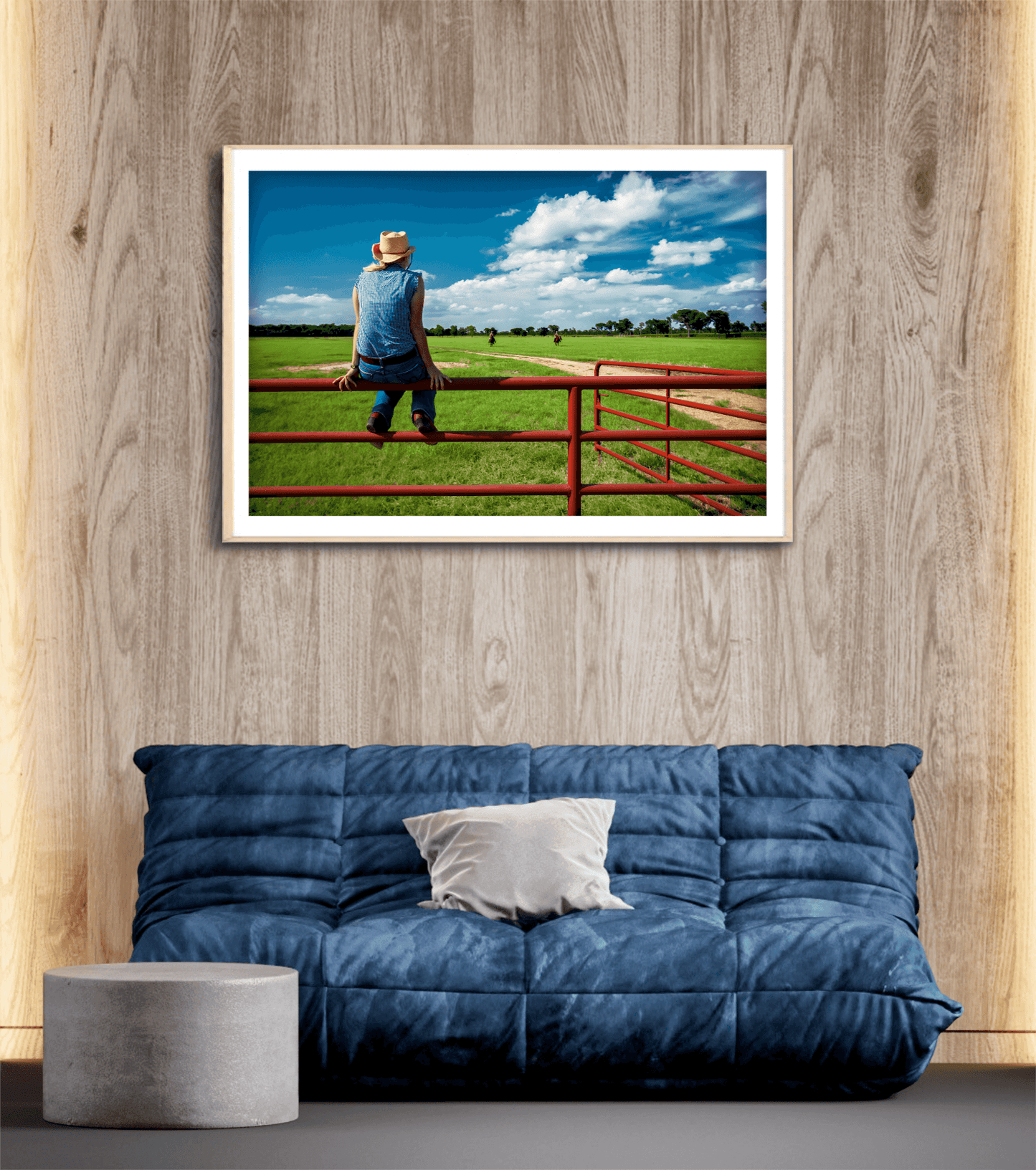 Coming Home: Waiting on the Fenceline at 44 Farms artwork mounted above a blue futon in a rustic wood-paneled room. Americana fine art with cowboy lifestyle theme.