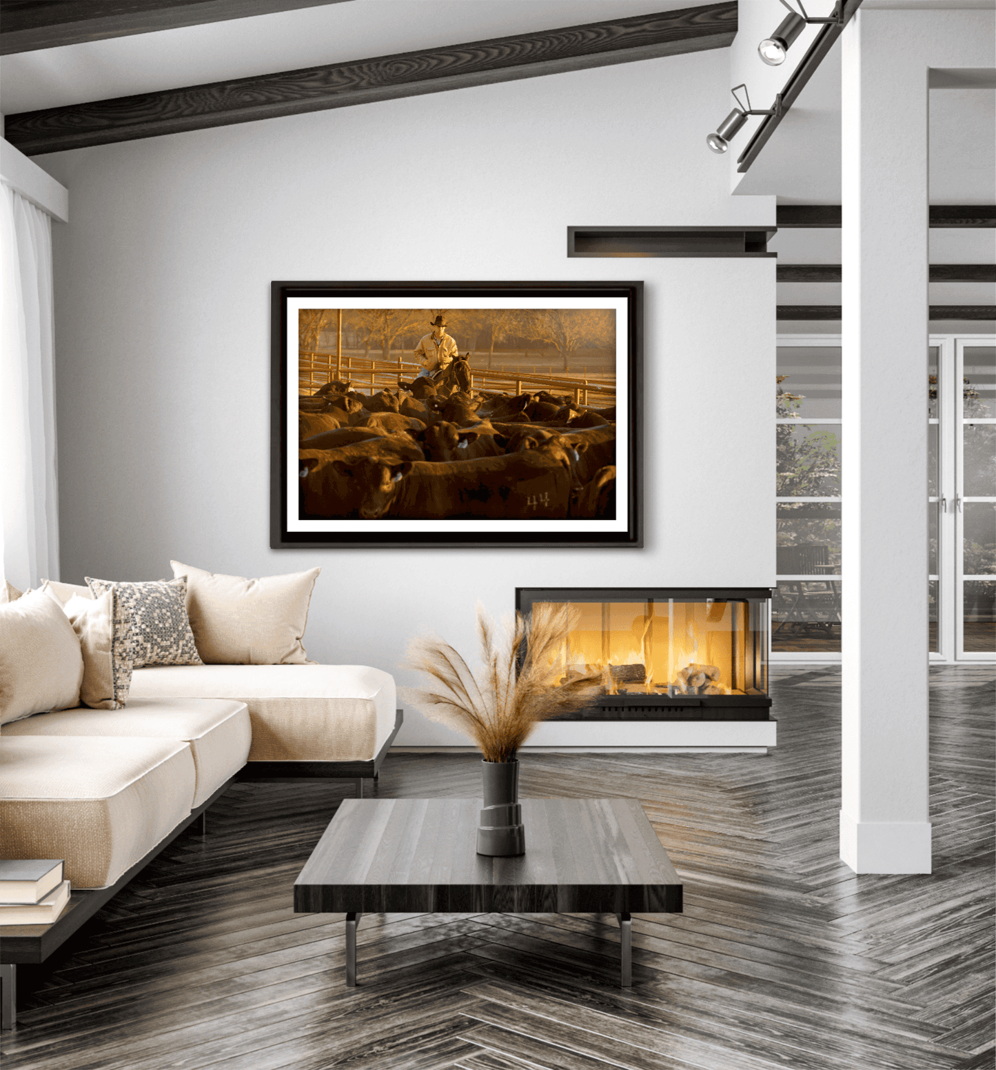 Golden hour cowboy and cattle artwork titled Morning Roundup at 44 Farms by Michael Hart showcased in a bright, contemporary living room with fireplace.