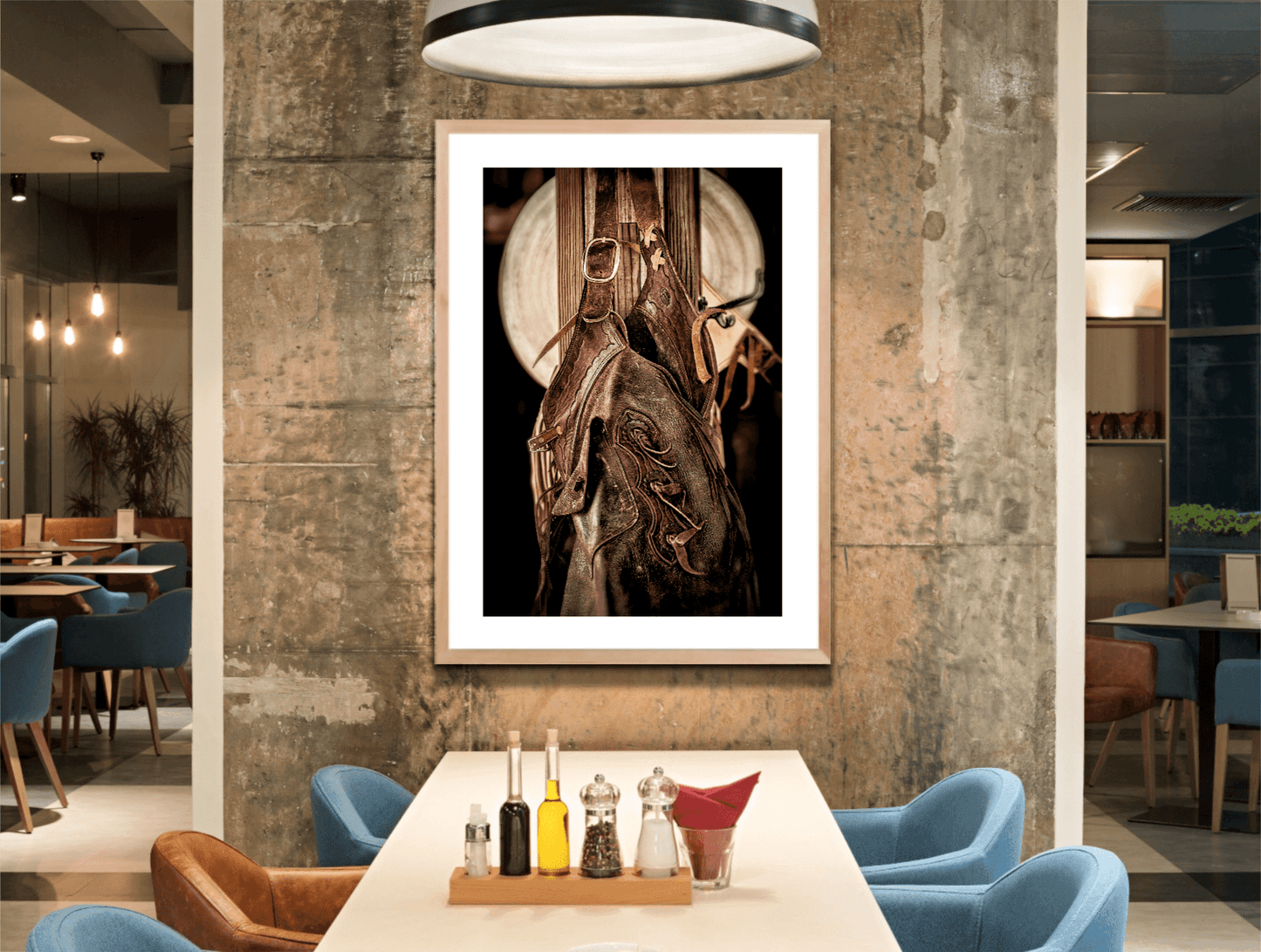 Framed sepia-toned Western fine art print of cowboy tack and hat displayed in a modern dining space, ideal for rustic interior decor.