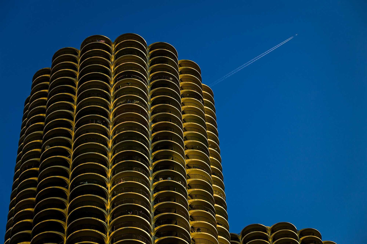 Marina Towers Photo - Chicago Icon Limited Edition | Hart features a striking view of the twin Marina City towers against a deep blue sky with a jet contrail. This collectible fine art print captures the bold architecture of a historic Chicago landmark.