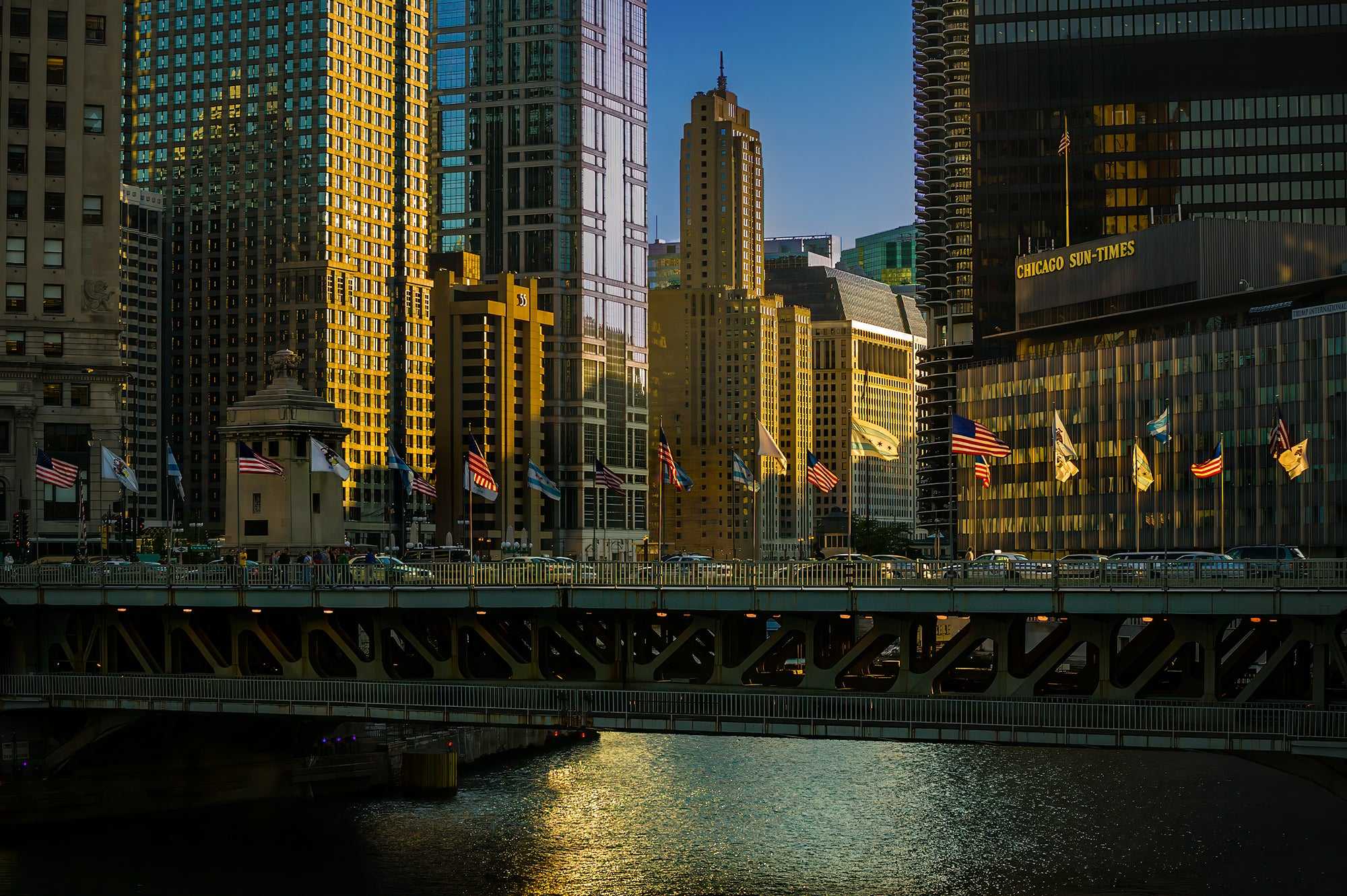 Chicago River #2 – Fine art photograph of the former Sun-Times Building glowing in golden-hour light with historic skyline reflections on water.