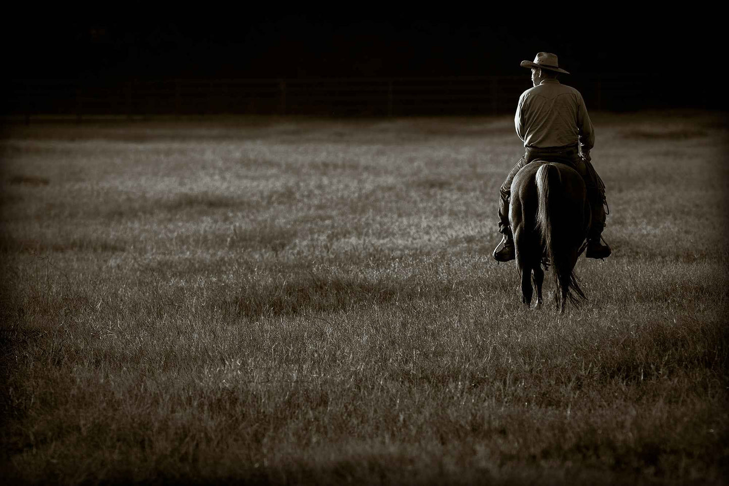 The Lone Rider – Texas cowboy on horseback at sunset in sepia tones, captured at 44 Farms. Fine art ranch photography in horizontal format.