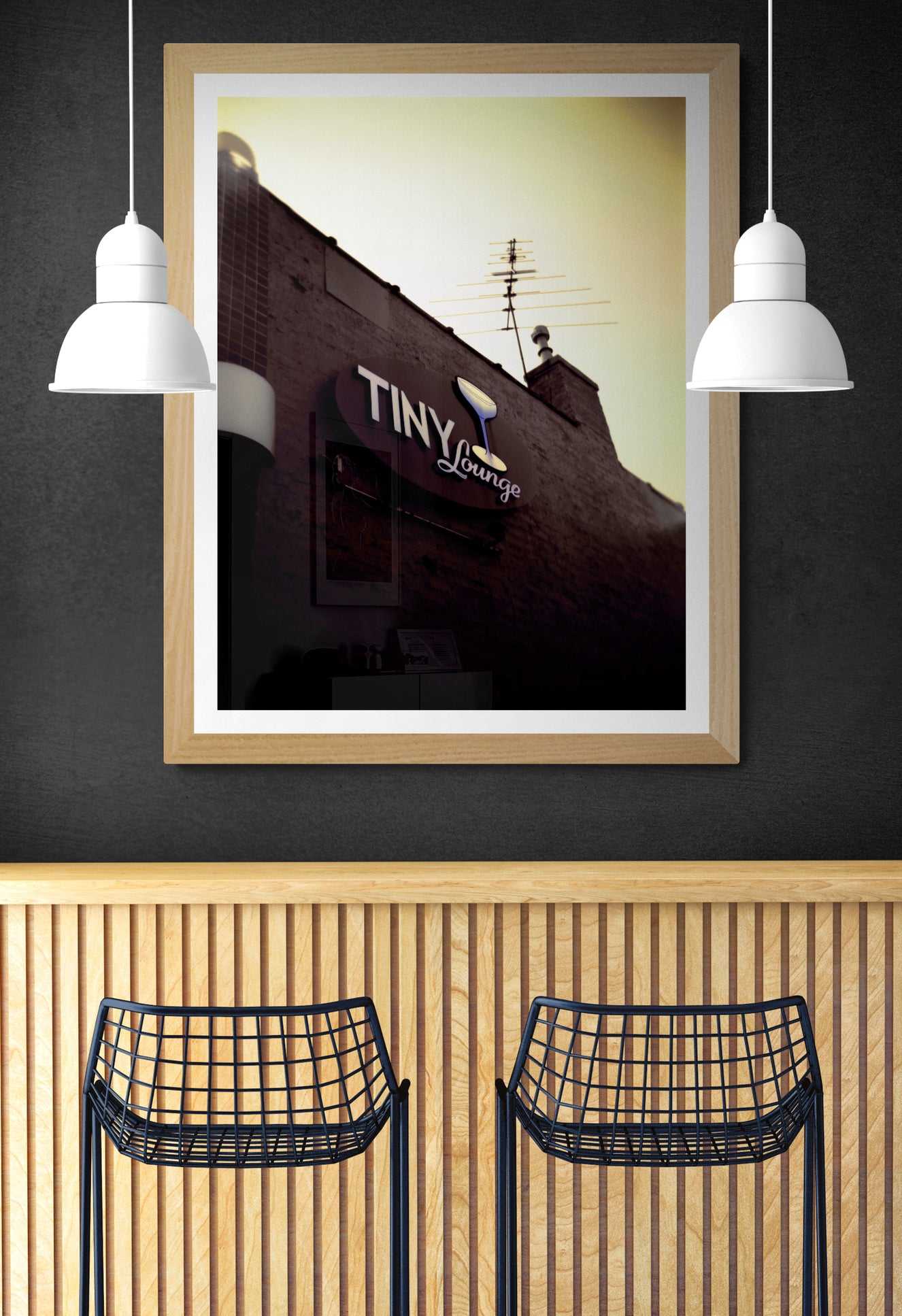 A print of an image, shot on a Holga camera, of the signage at The Tiny Lounge, an iconic small bar that used to exist in Chicago, Illinois, shown on the wall of a room setting