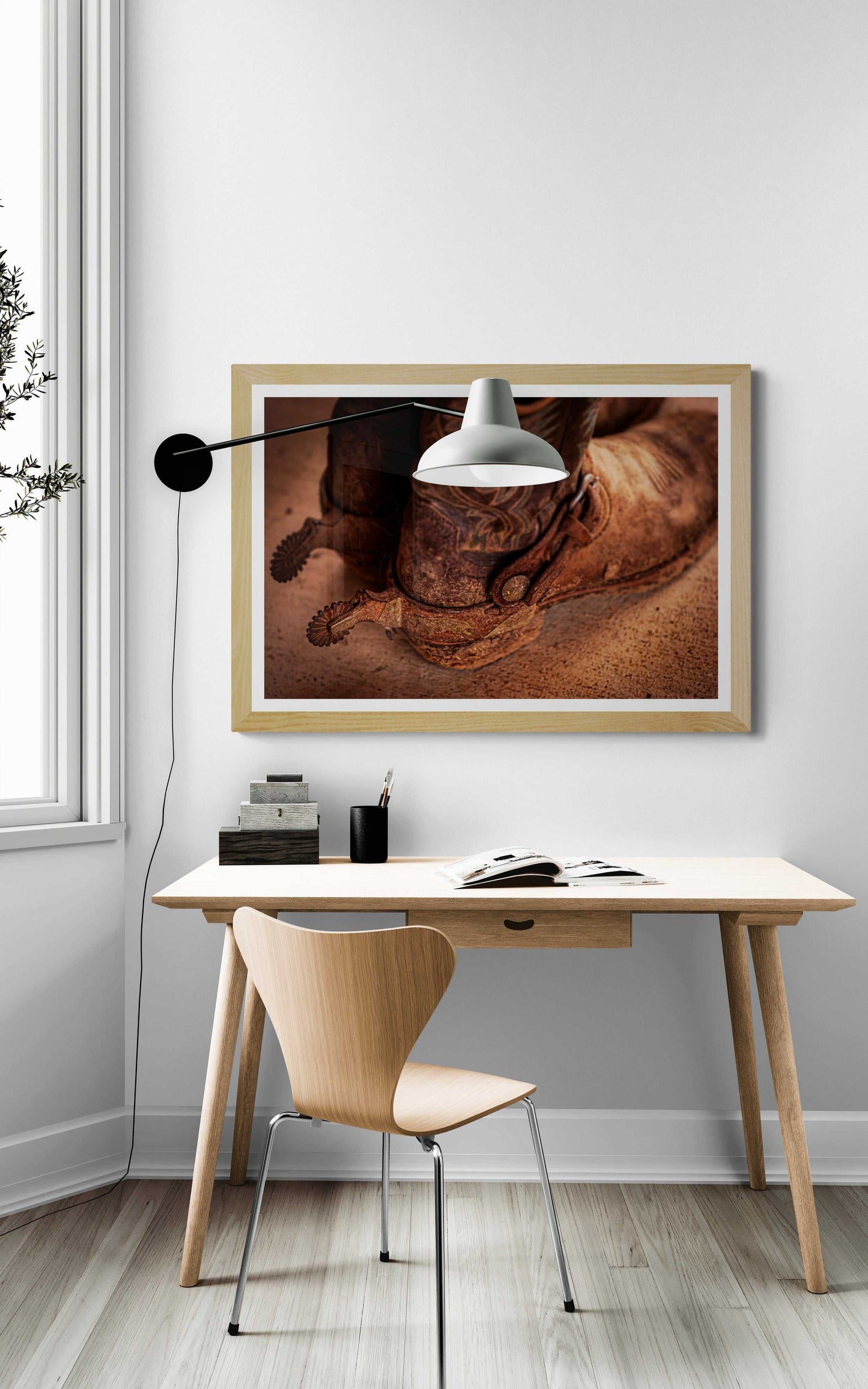 Western fine art print 'Well Worn – A Real Texan’s Cowboy Boots' by Michael Hart framed above a minimalist desk, perfect for rustic or Southwestern home decor themes.
