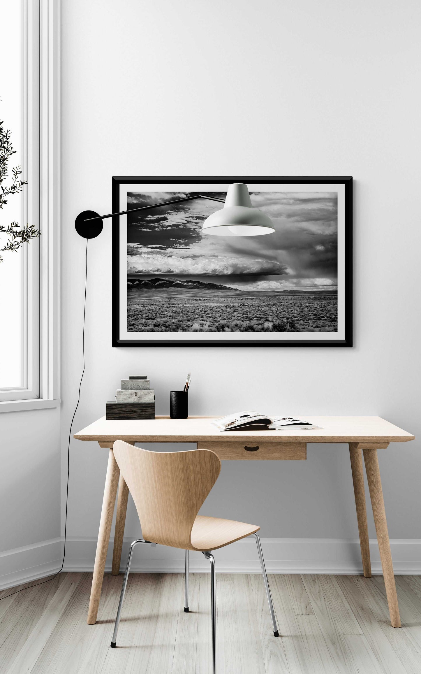 A black and white framed image of summer storm clouds over eastern Wyoming shown on the wall in a room setting