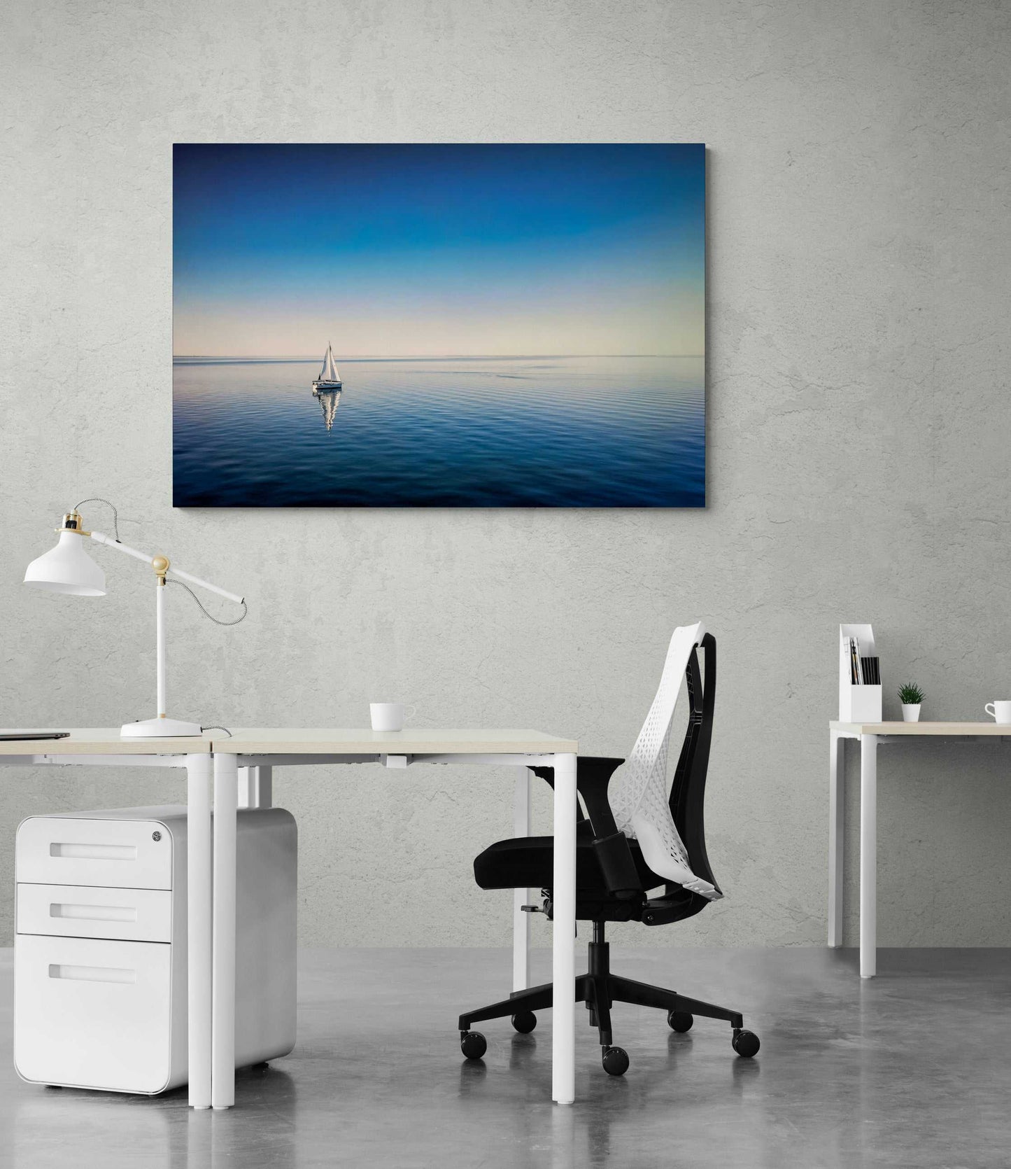 The Calm – Sailboat on Calm Blue Galveston Bay print brings tranquil coastal vibes to a contemporary office space with minimalist decor and gray walls.