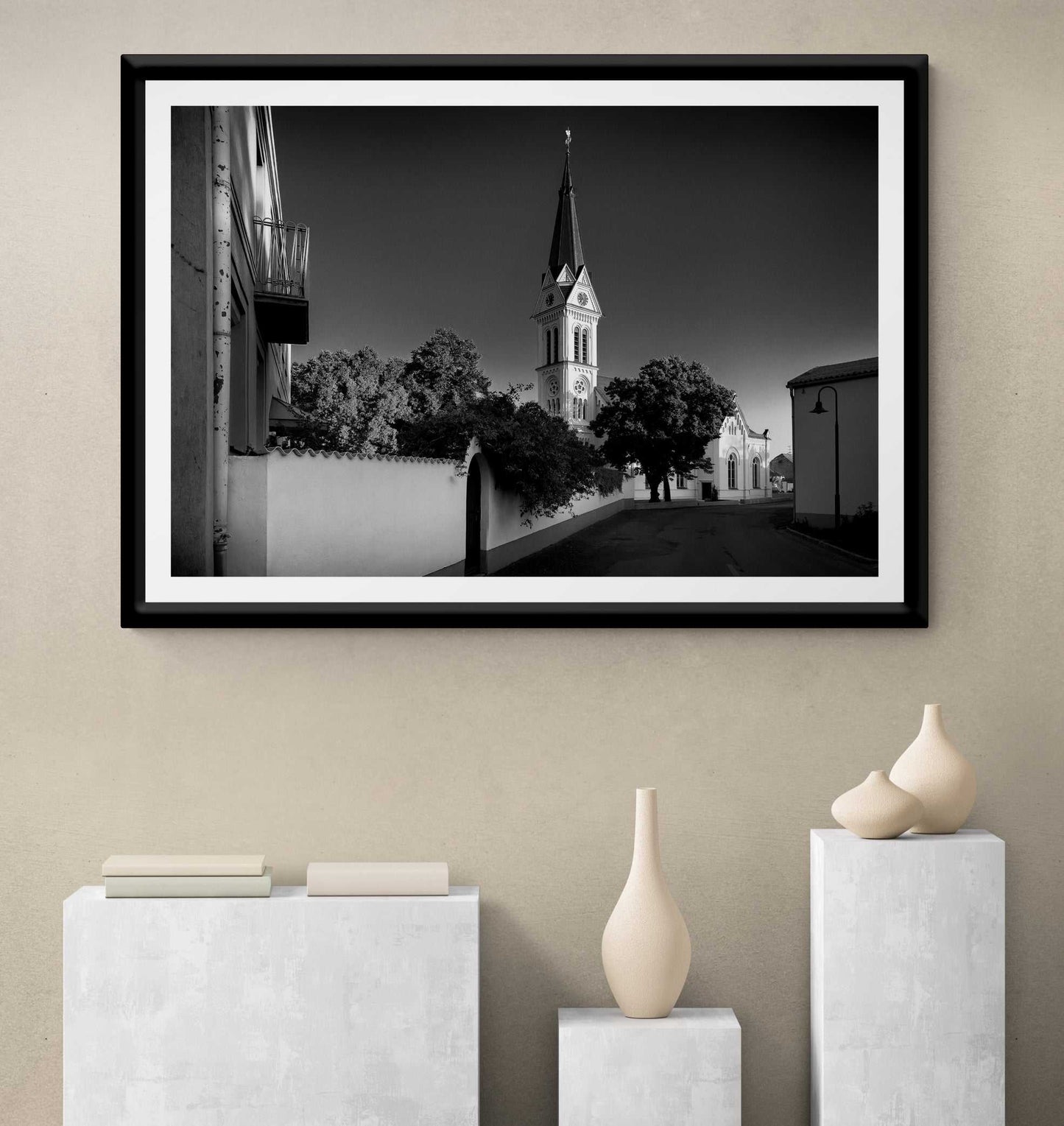A framed print of the black and white image of an Autrian Church and Steeple in a room setting