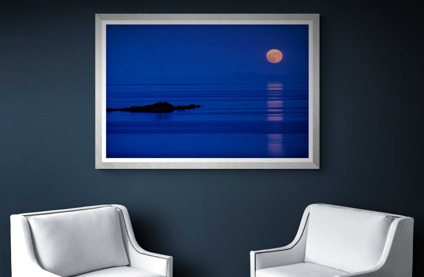 Islay Moonrise over the Atlantic – Fine Art Twilight Photography framed on a dark wall between two white chairs, perfect for elegant and calming interior design themes.