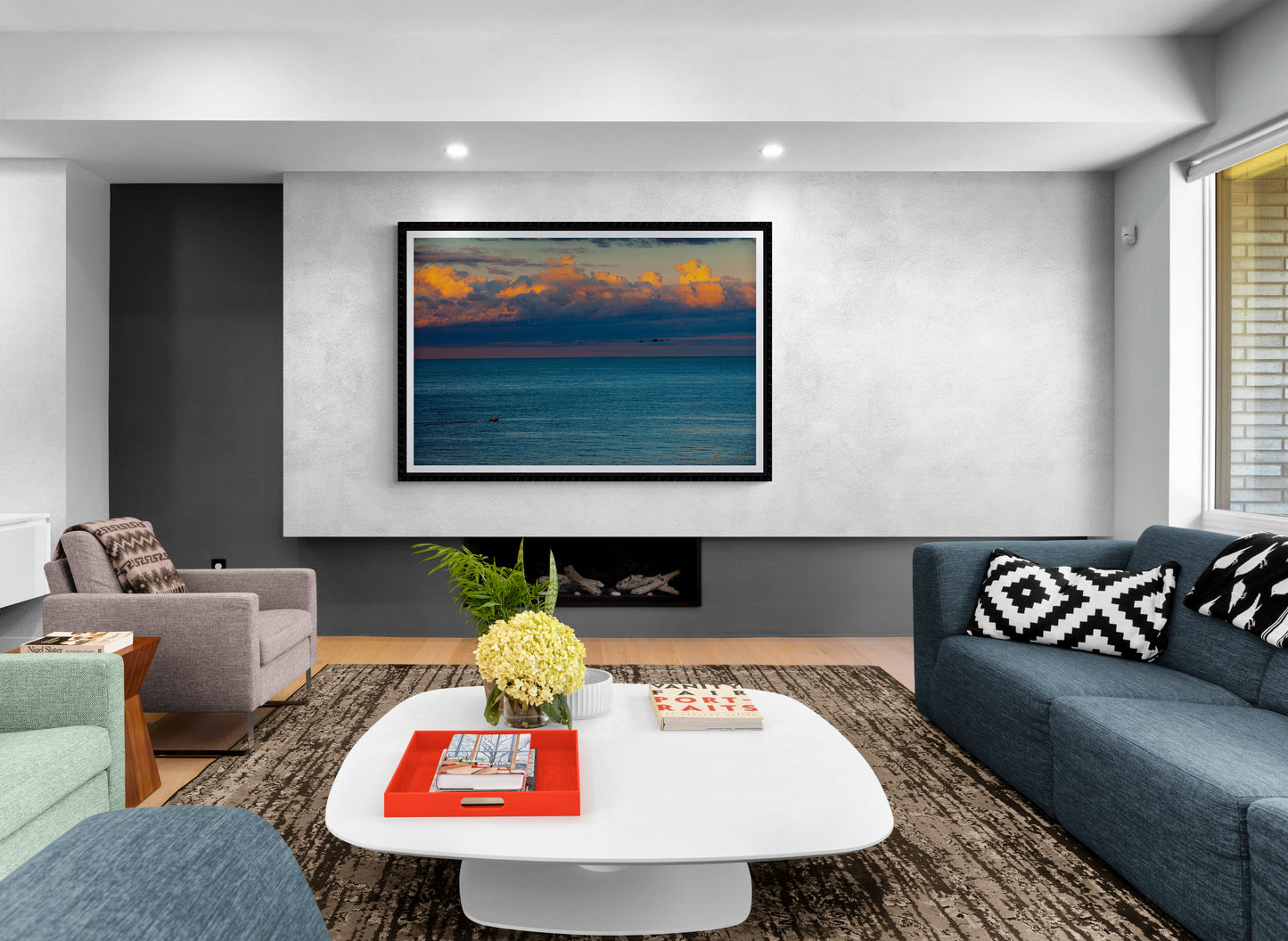 Modern living room featuring The Race – Small Boat and Birds in a New England Coastal Sunset framed print as a centerpiece above a sleek fireplace.
