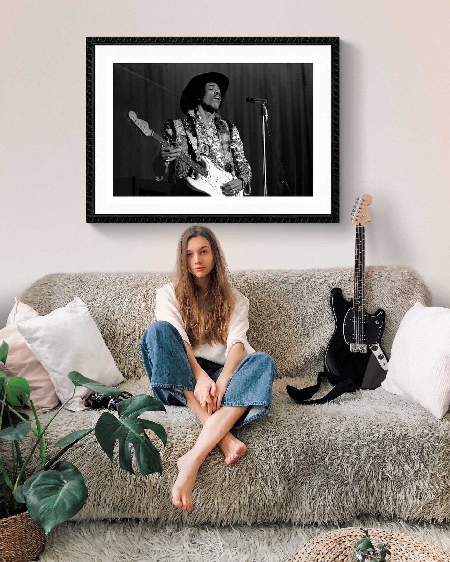 Jimi Hendrix black and white framed print above cozy sofa with guitar, blending vintage rock art with modern home decor aesthetics.