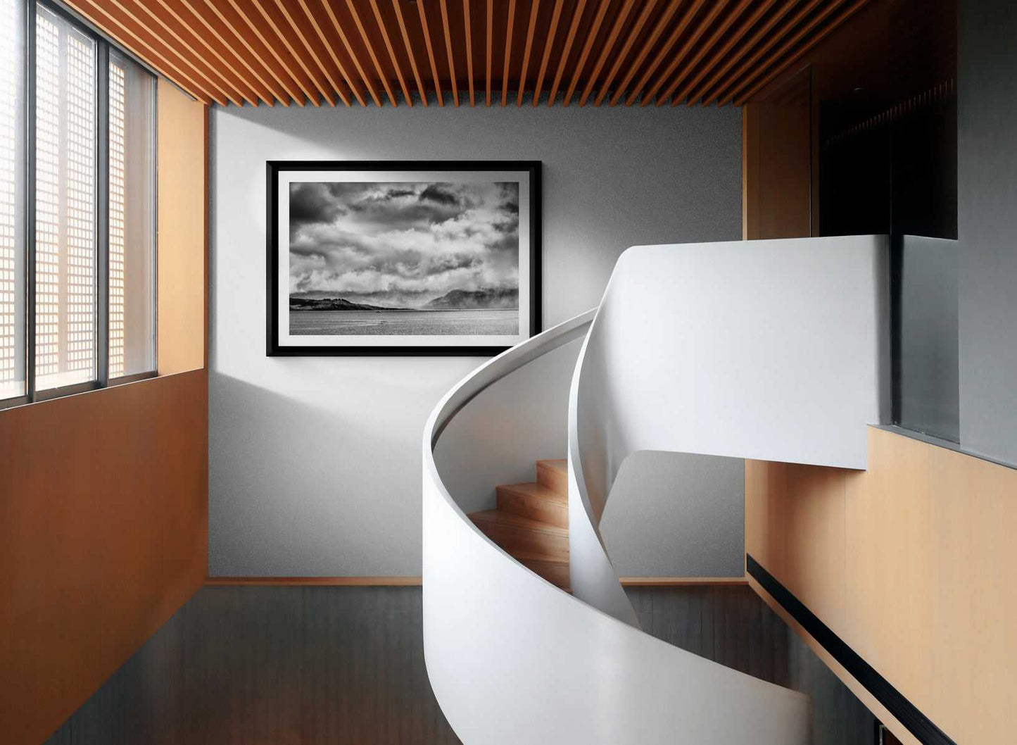 Framed Storm Clouds Kyleakin - Isle Of Skye Print by Michael Hart on a grey wall above a spiral staircase. A dramatic monochrome print for modern architectural spaces.
