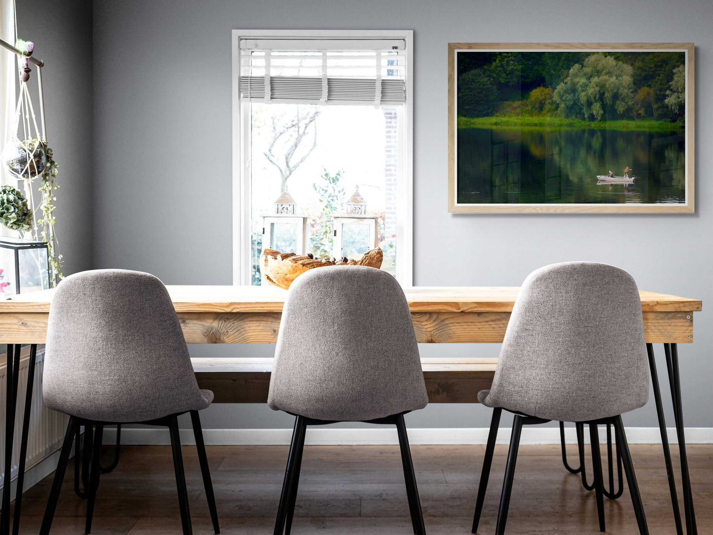 Framed fine art print 'Fishermen on Linlithgow Loch – A Scene of Light, Gesture, and Color' displayed in modern dining room with gray chairs. Tranquil Scottish landscape enhances interior design.