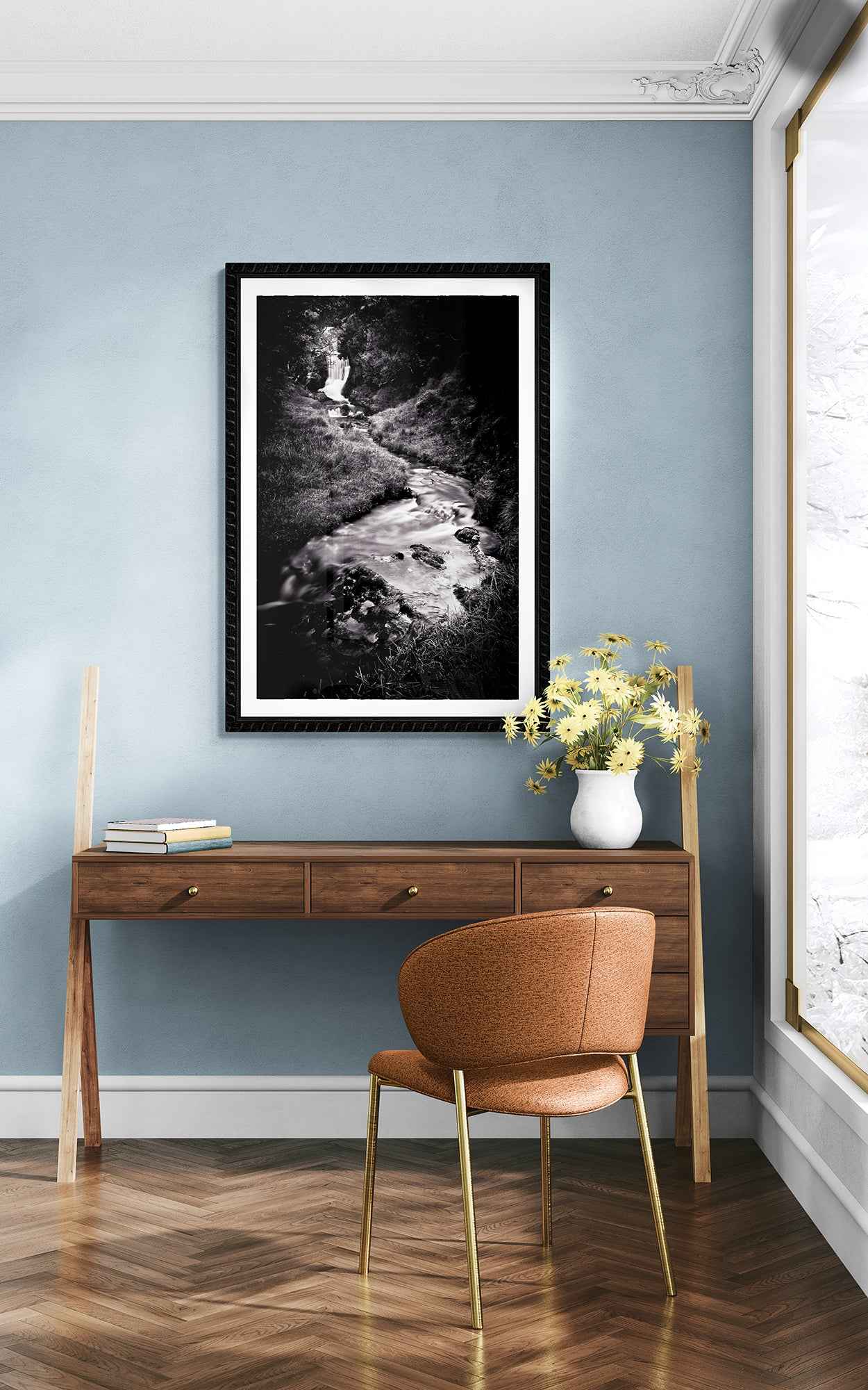Scottish Highlands waterfall photo print in a stylish blue-walled room with wooden desk and orange chair, blending fine art with modern decor.