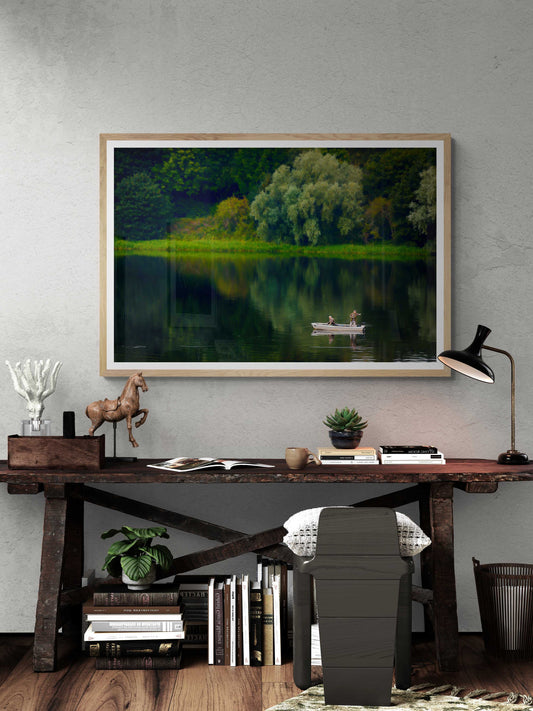 Fishermen on Linlithgow Loch – A Scene of Light, Gesture, and Color framed art print above rustic desk. Tranquil Scottish lake with boat and lush trees.