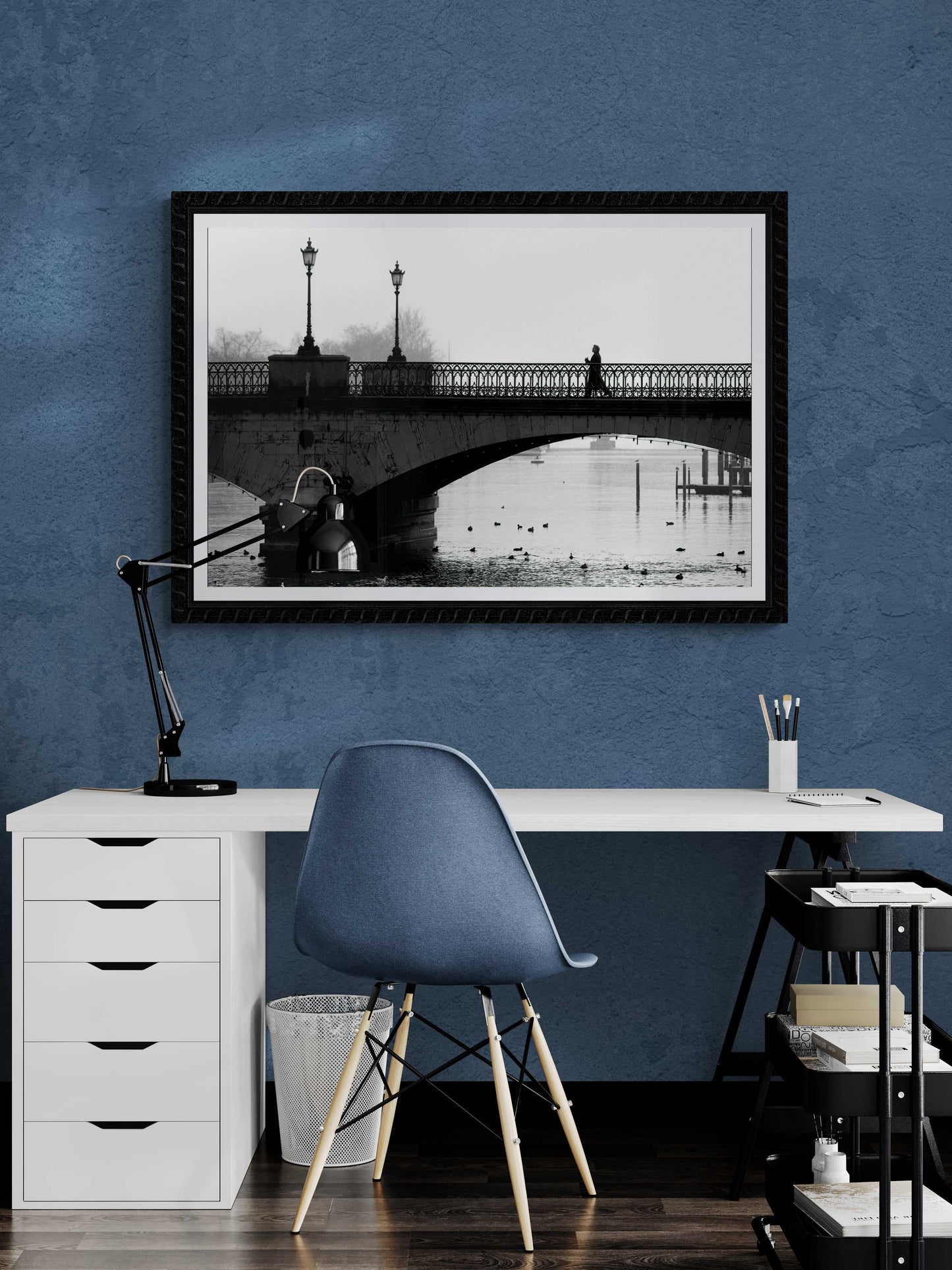 Zurich Series #1 – A Man on the Bridge, Zurich in Black and White – Fine Art Print by Michael Hart framed above a white desk in a stylish blue home office setup.