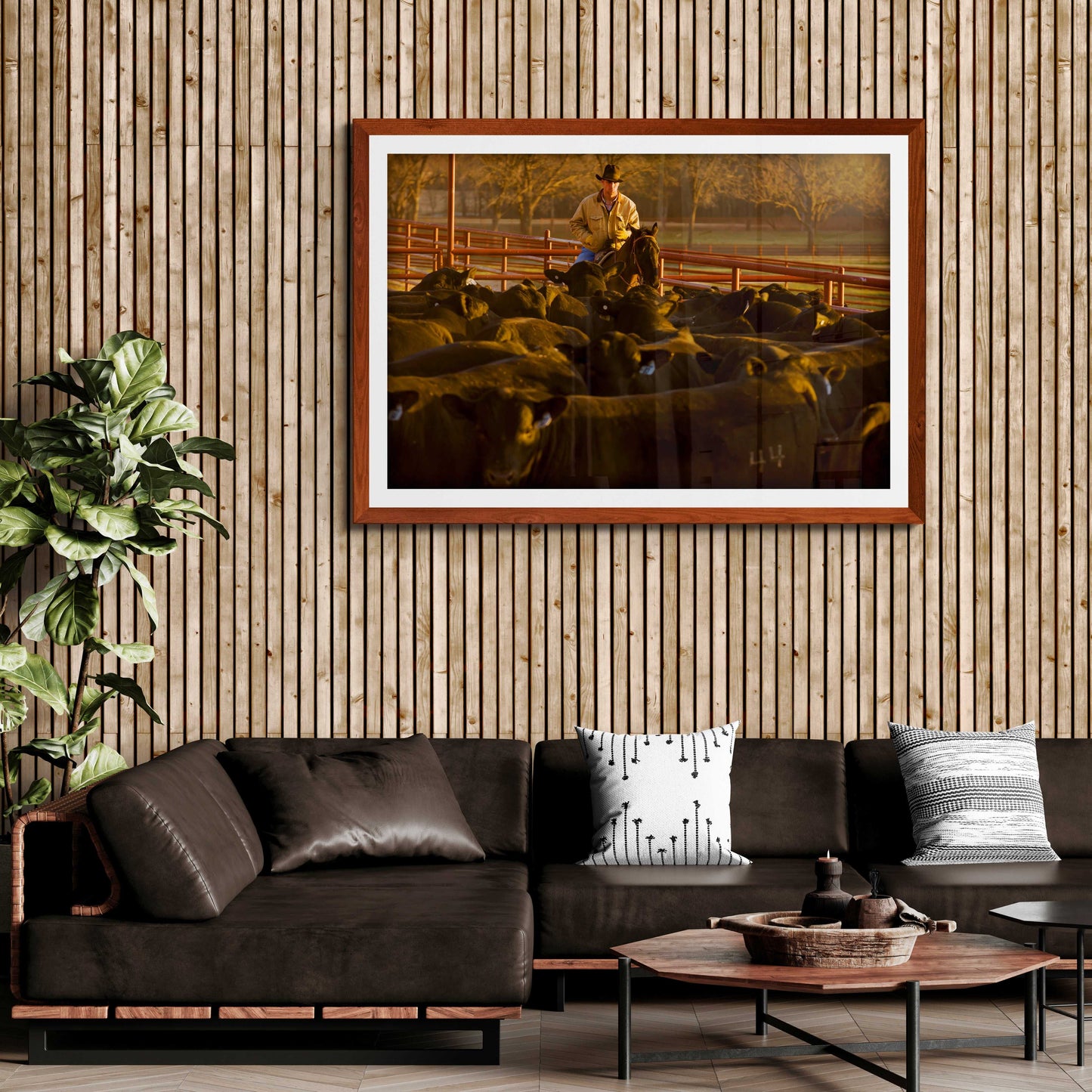Rustic-themed living room with wood paneling featuring Morning Roundup at 44 Farms cowboy and cattle fine art print by Michael Hart in a brown frame.