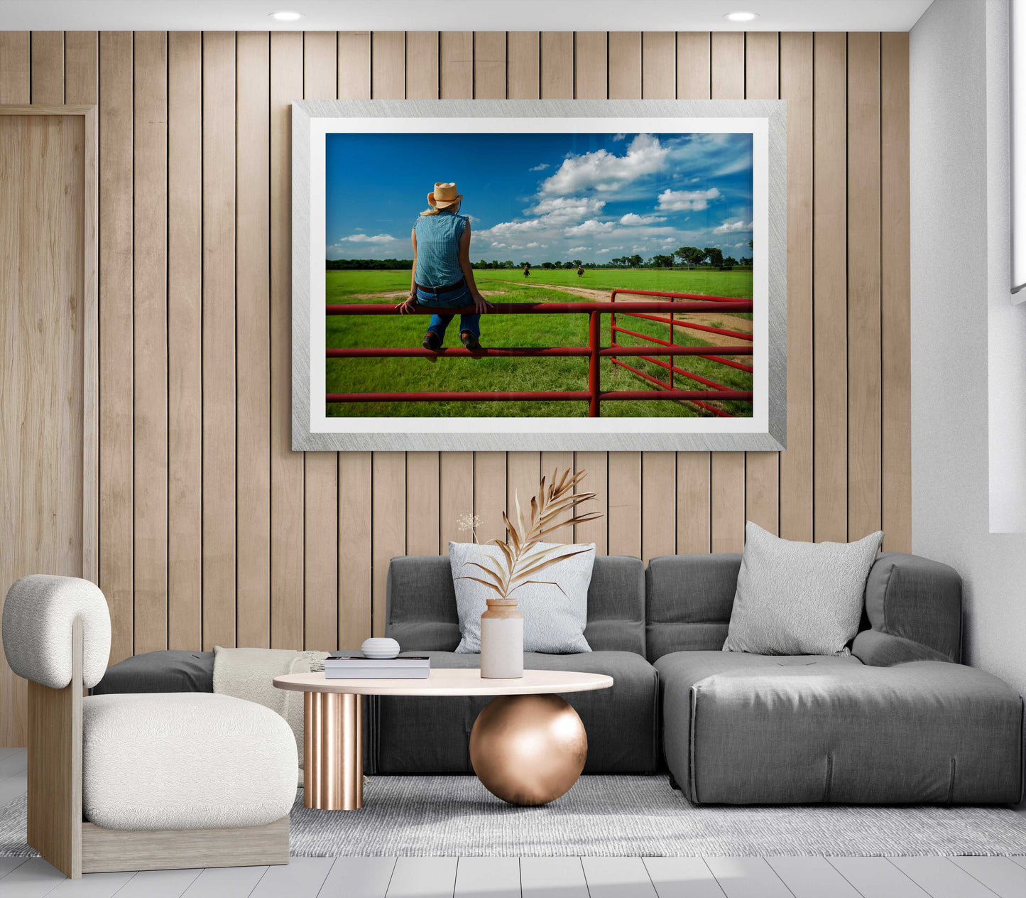 Coming Home: Waiting on the Fenceline at 44 Farms fine art print in a cozy living room with wood panel walls and gray sectional. Texas ranch culture wall decor.