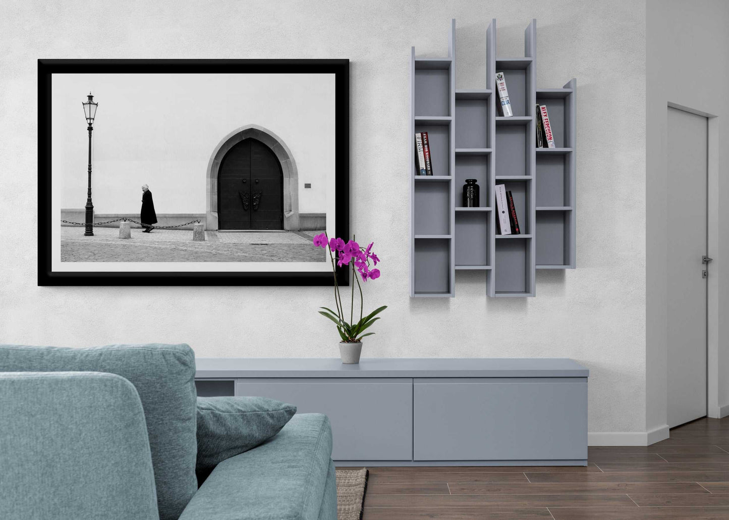 Zurich Series #2 – The Woman and the Church, Black and White Fine Art Print by Michael Hart mounted above a blue sofa and modern shelving in a minimalist living room.