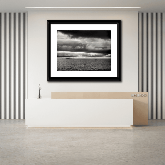 Framed black and white seascape photograph of the Atlantic Ocean at Marshall Point, Maine displayed above a modern office reception desk