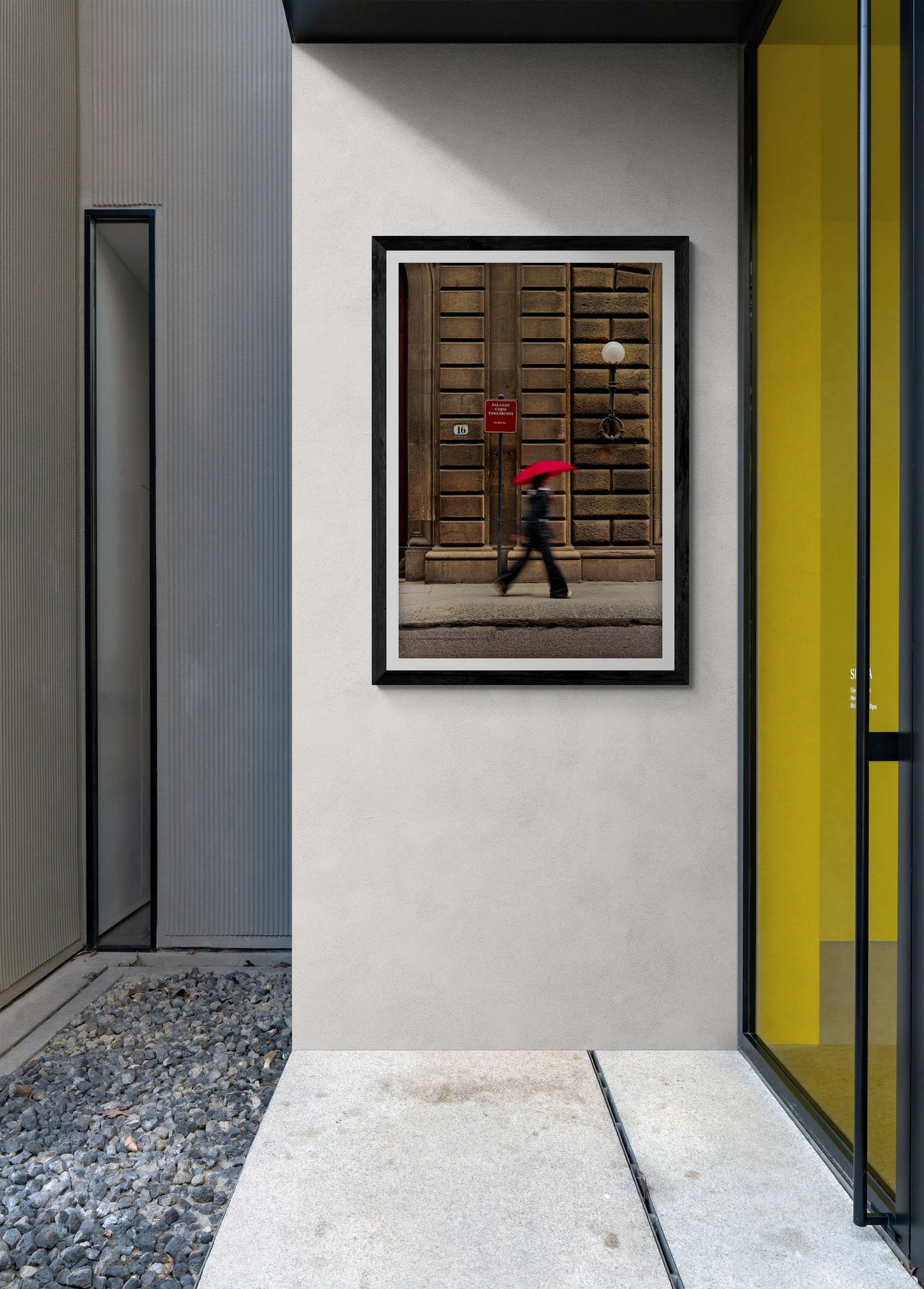 Modern interior wall with framed street photograph of a person with red umbrella in Florence