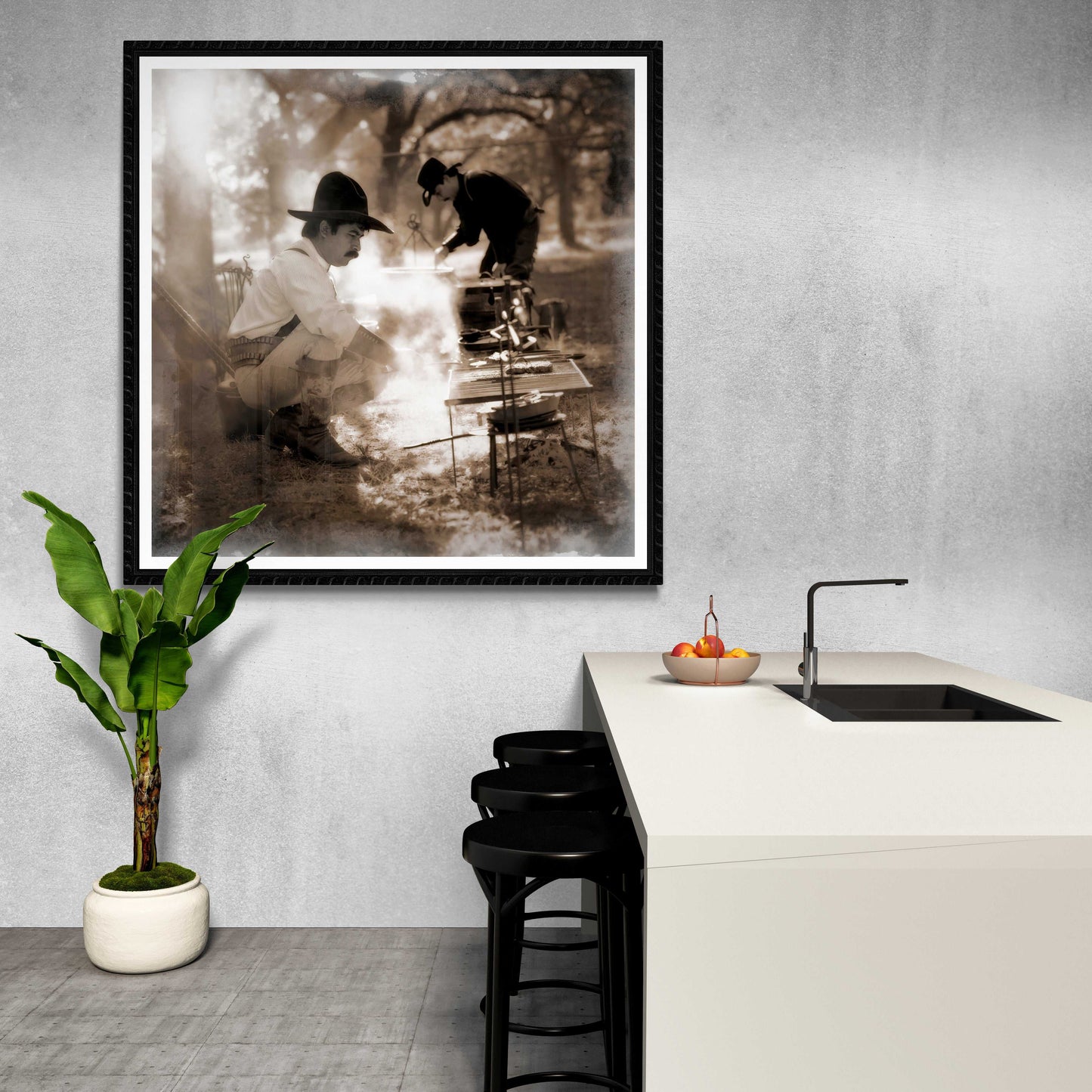 Square format cowboy campfire photo in black frame hung in modern kitchen, blending Western lifestyle photography with minimalist interior design.