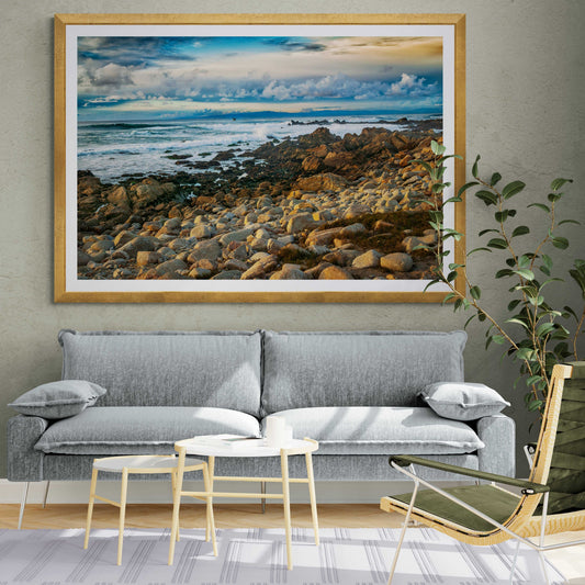 Framed Monterey Bay – Vibrant California Seascape Limited Edition Print by Michael Hart displayed above a modern gray sofa in a stylish living room.
