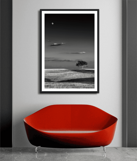 Framed Moonrise at Sunset – Black and White Texas Landscape Print by Michael Hart displayed above a red modern sofa in a minimalist interior.