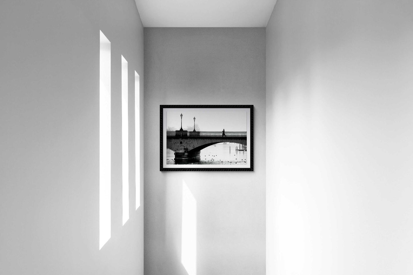 Zurich Series #1 – A Man on the Bridge, Zurich in Black and White – Fine Art Print by Michael Hart hanging in a minimalist hallway with natural light streaming through vertical windows.