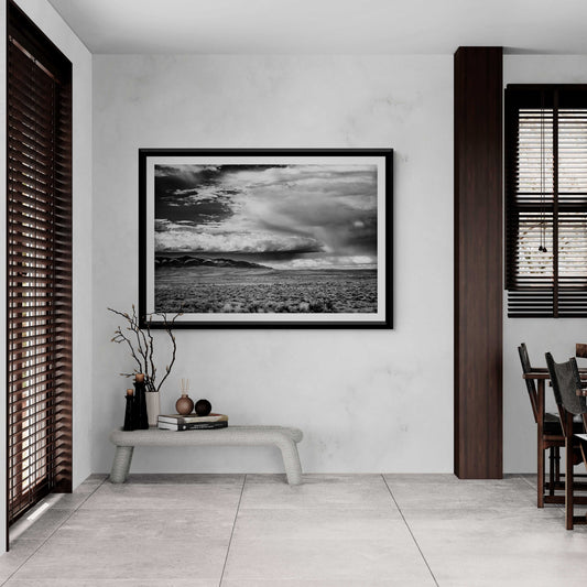 A black and white framed image of summer storm clouds over eastern Wyoming shown on the wall in a contemporary dining room setting