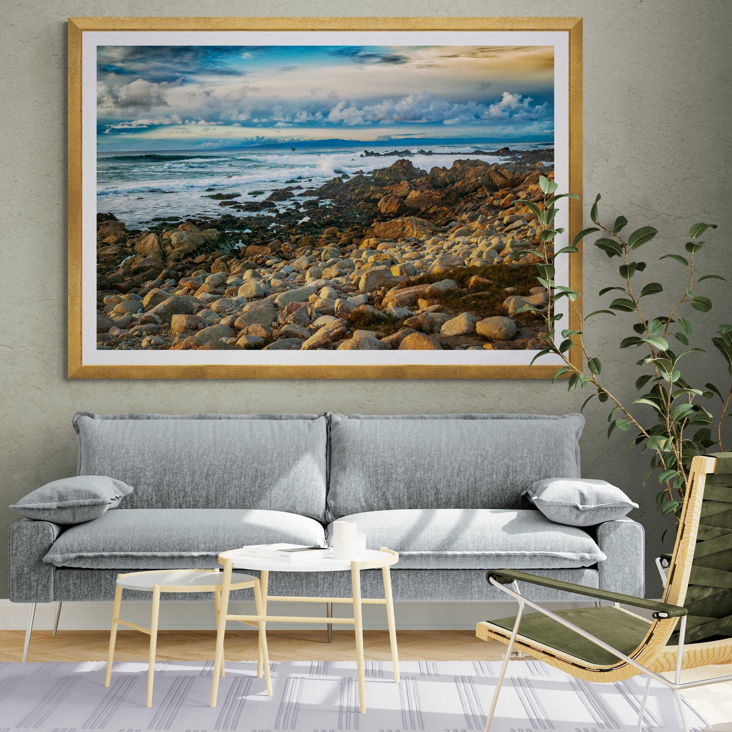 Framed Monterey Bay – Vibrant California Seascape Limited Edition Print by Michael Hart displayed above a modern gray sofa in a stylish living room.