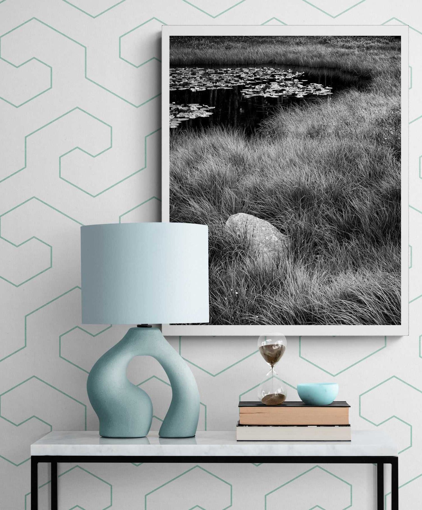 Framed Wyoming nature print 'Pond Boulder' by Michael Hart displayed above a modern console with a sculptural lamp and books in a home decor setting.