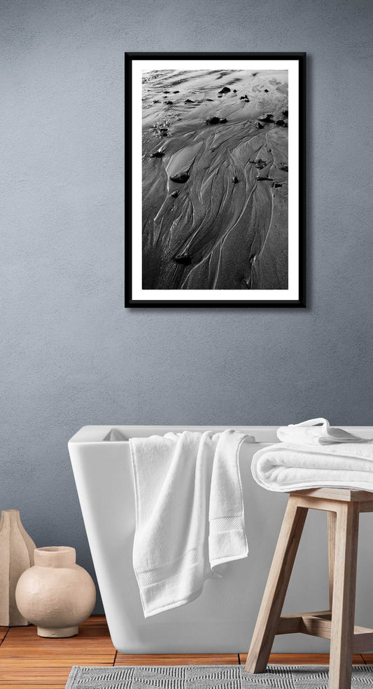 Black and white sand pattern artwork 'Traces #3' displayed in a modern bathroom, adding minimalist coastal elegance to home decor.