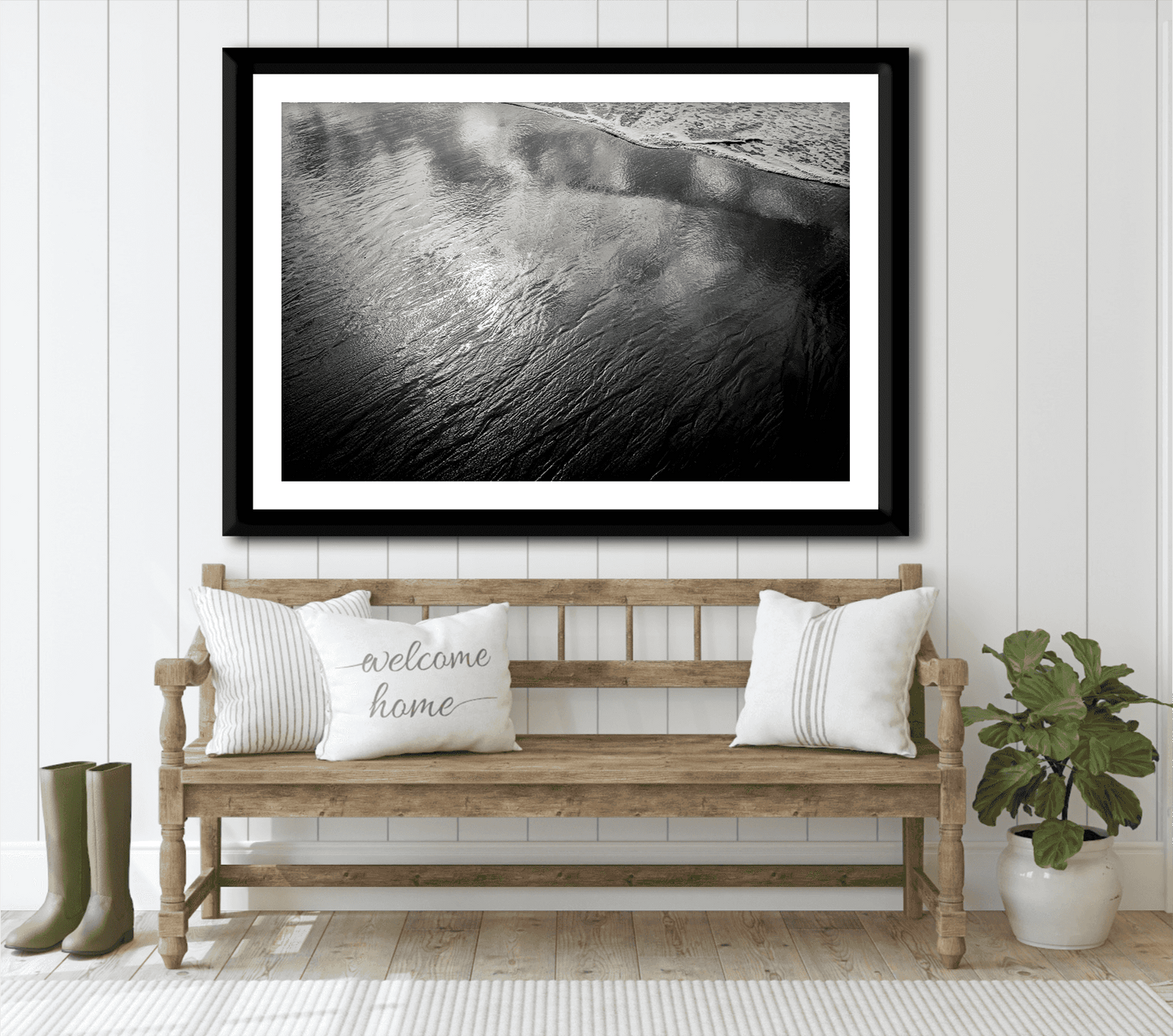 Coastal-themed entryway with framed 'Traces #4 – Reflections at the Sea Edge, Maine' black and white print above wooden bench and welcome pillow.
