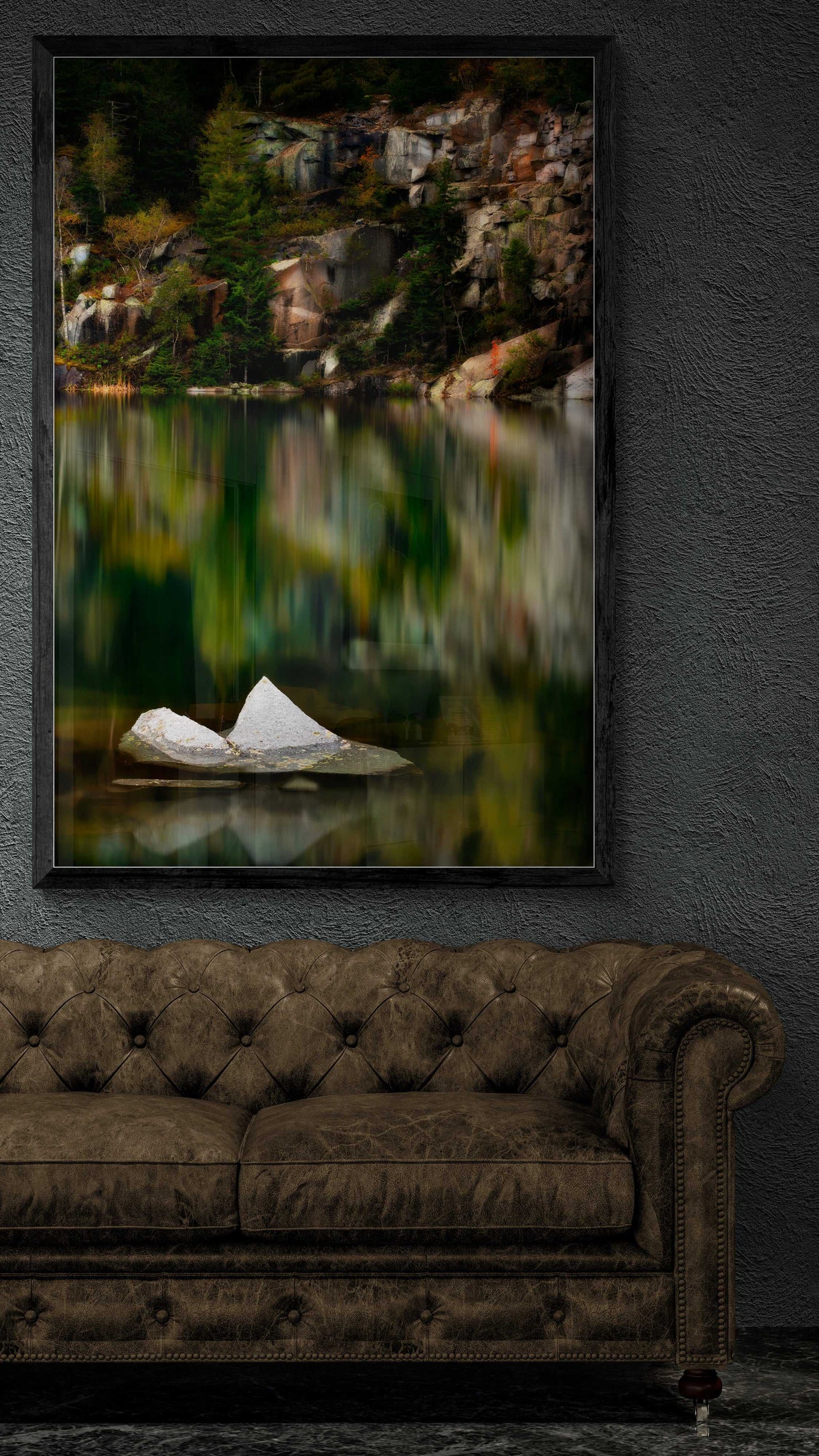 Framed print of The Sentinel – A Lone Rock Emerges Above The Quarry Waterline, Maine displayed above a brown tufted sofa, enhancing rustic interior decor.