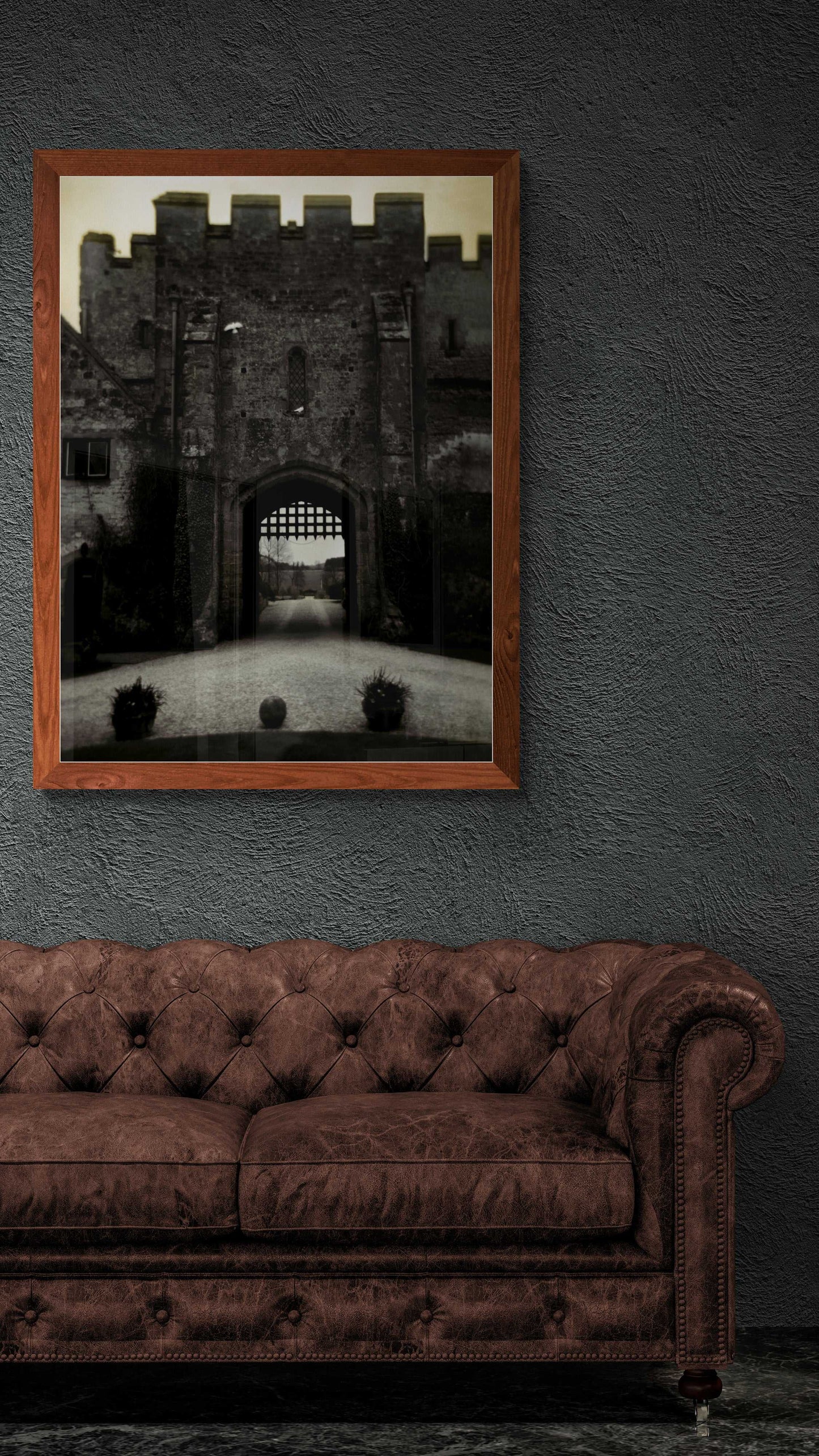 Amberley Gate – Limited Edition Fine Art Photograph in a dark wood frame above a leather sofa. Enhances moody, classic interior design with castle imagery.