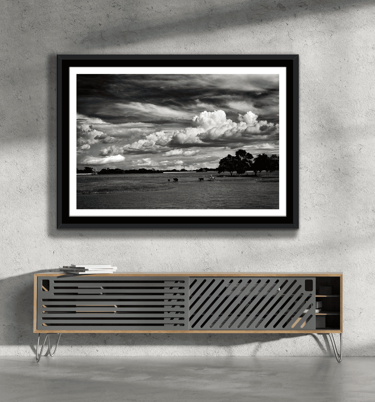 Texas ranch life artwork 'Under a Texas Sky' in black and white, framed above a minimalist console in a concrete wall living space.