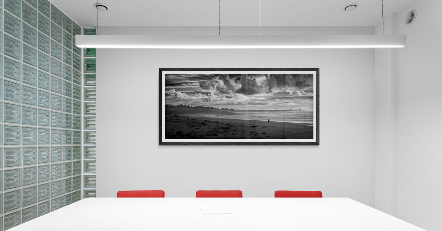 Framed black and white panoramic photograph of a person and dog on Monterey Bay displayed on a wall in a modern conference room