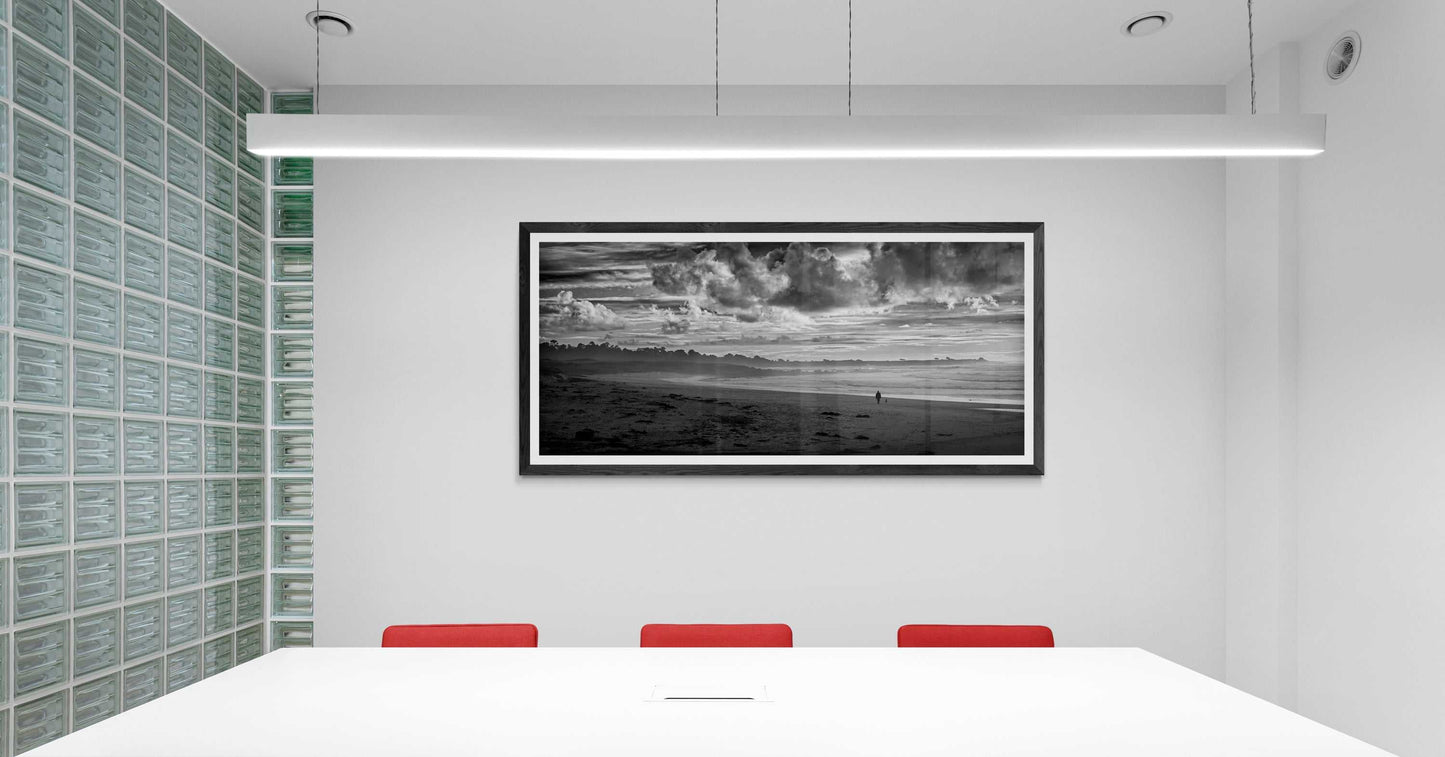 Framed black and white panoramic photograph of a person and dog on Monterey Bay displayed on a wall in a modern conference room