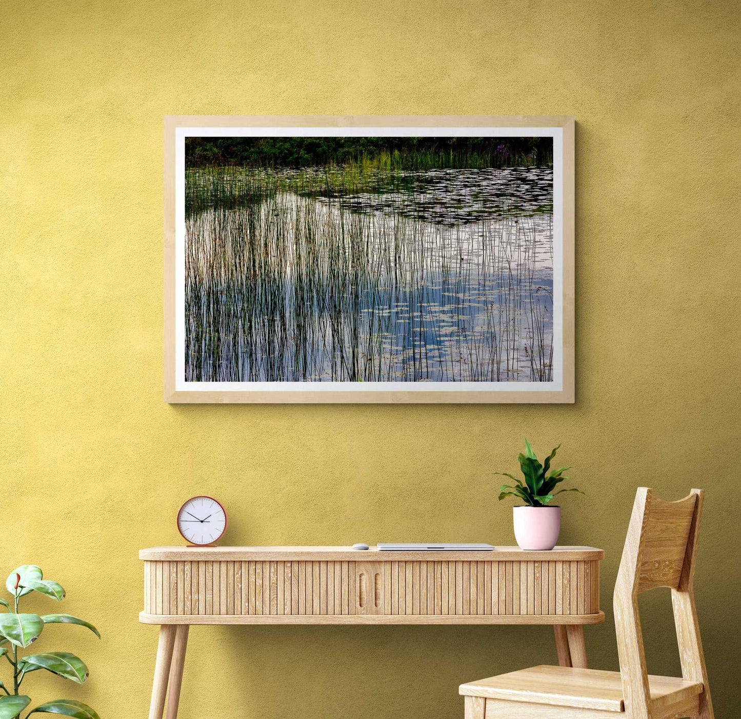Reeds and Water limited edition Scotland print on yellow wall above a wooden desk, adding natural tranquility to home workspace decor.