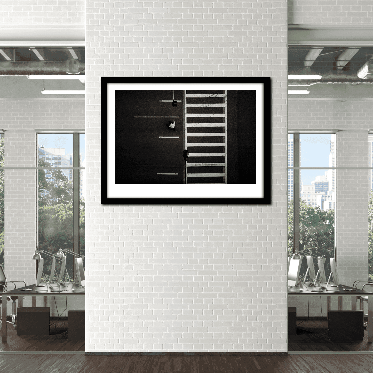 Chicago Crosswalk – Limited Edition Urban Street Photography by Michael Hart displayed in modern office with white brick wall. Black and white overhead photo features bold crosswalk lines and lone pedestrian.